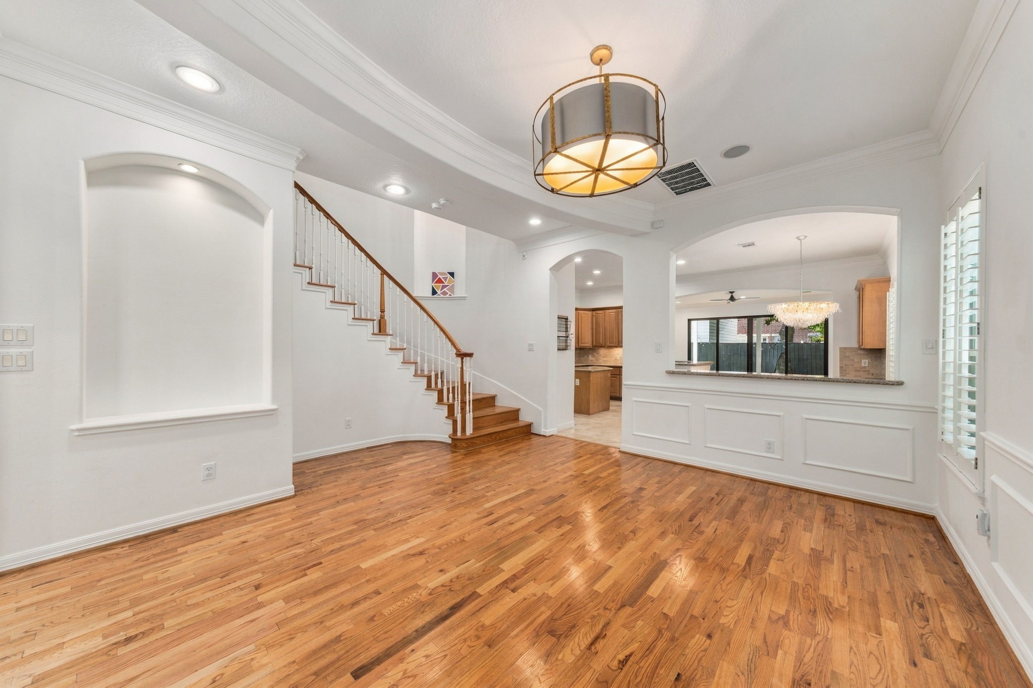 Another view of the formal dining room, showcasing the hardwood flooring, architectural details & open connection to the kitchen.