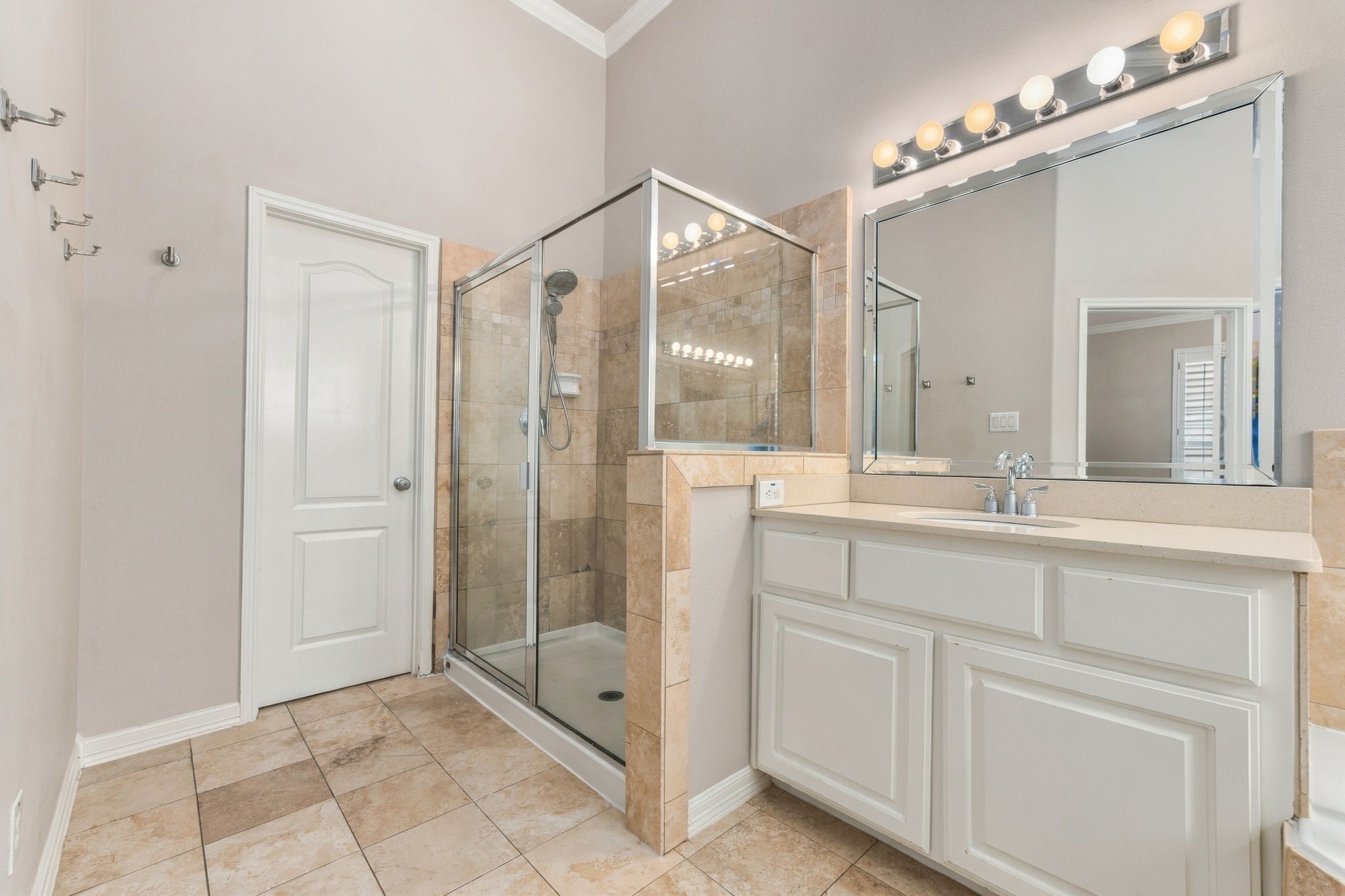 A separate glass-enclosed shower with tile surround & handheld showerhead completes the primary bath.