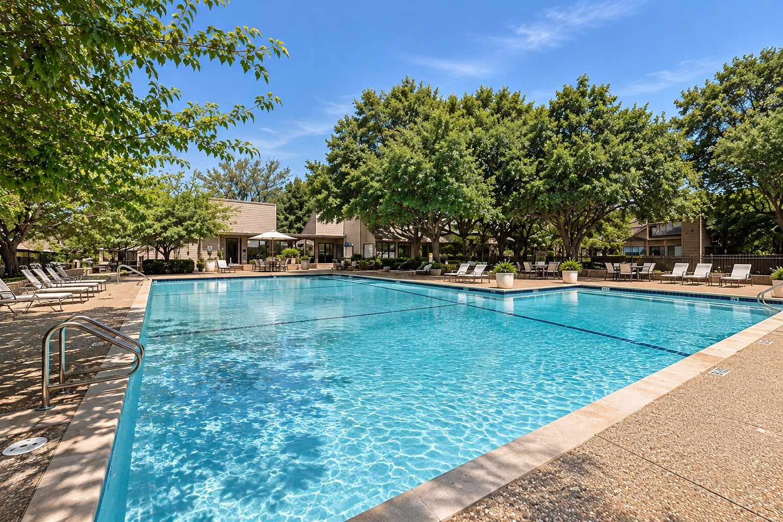 Resort-style community swimming pool surrounded by lounge seating, mature trees, and relaxing outdoor spaces.