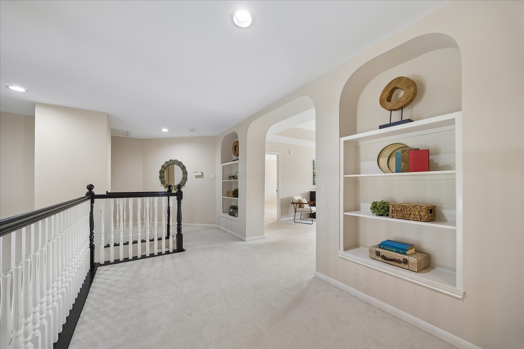 The spacious upstairs landing is accented by elegant arched niches with built-in shelving, creating an inviting transition between the home's secondary living spaces and bedrooms.