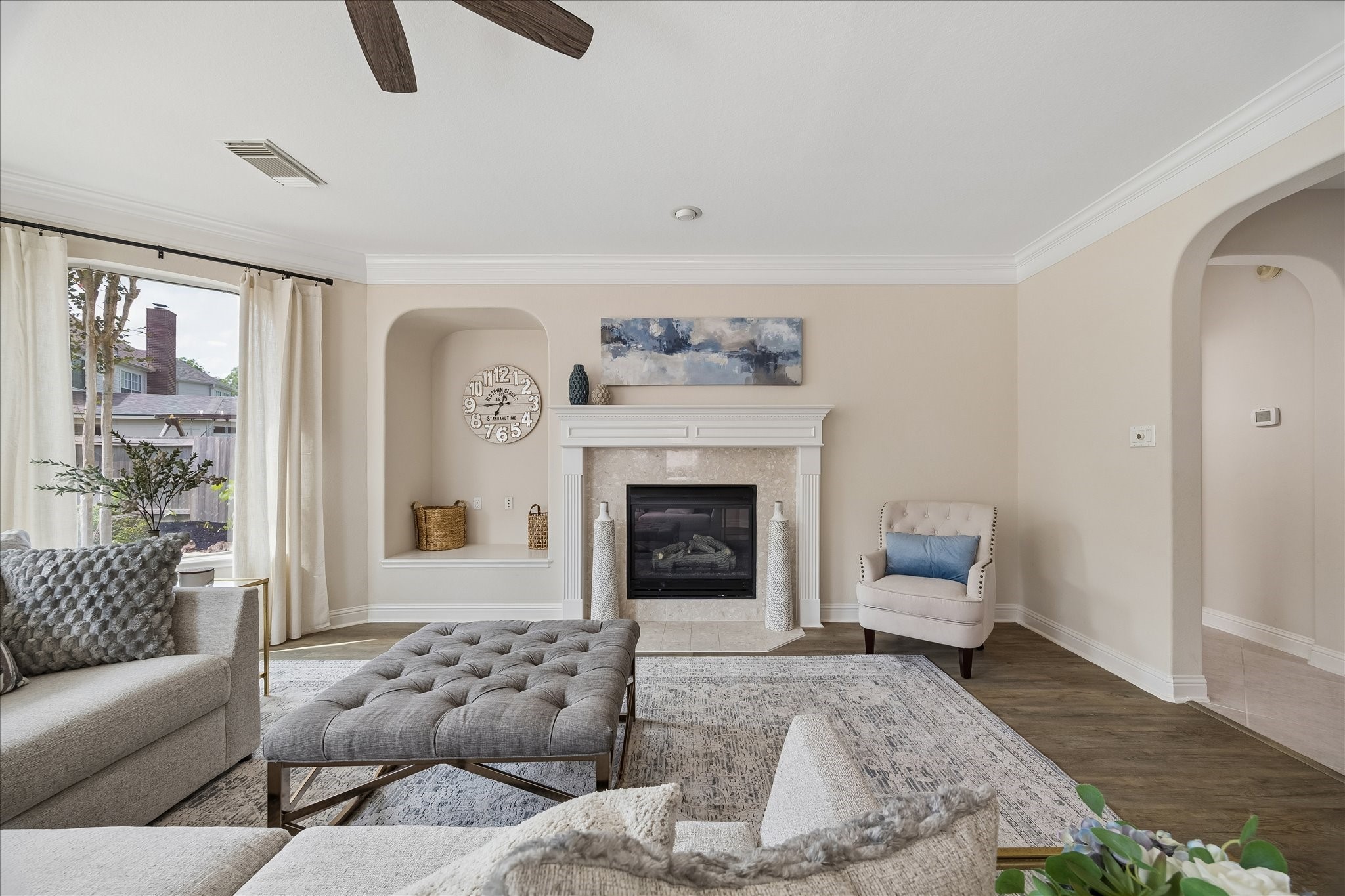 Architectural niches and a striking fireplace surround add warmth and character to this inviting gathering space. Expansive windows provide peaceful views of the backyard.