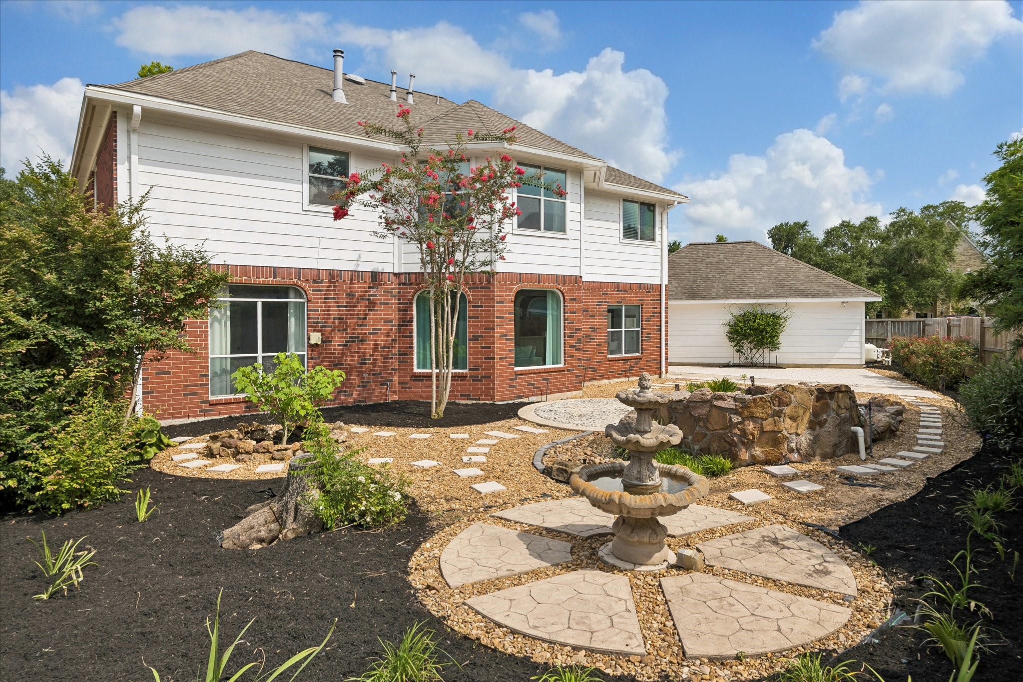 A custom rock feature and decorative bird bath bring a tranquil atmosphere to this low-maintenance backyard. Curved pathways and mature landscape add charm and character throughout the outdoor space. A custom rock feature and decorative bird bath bring a tranquil atmosphere to this low-maintenance backyard. Curved pathways and mature landscape add charm and character throughout the outdoor space.