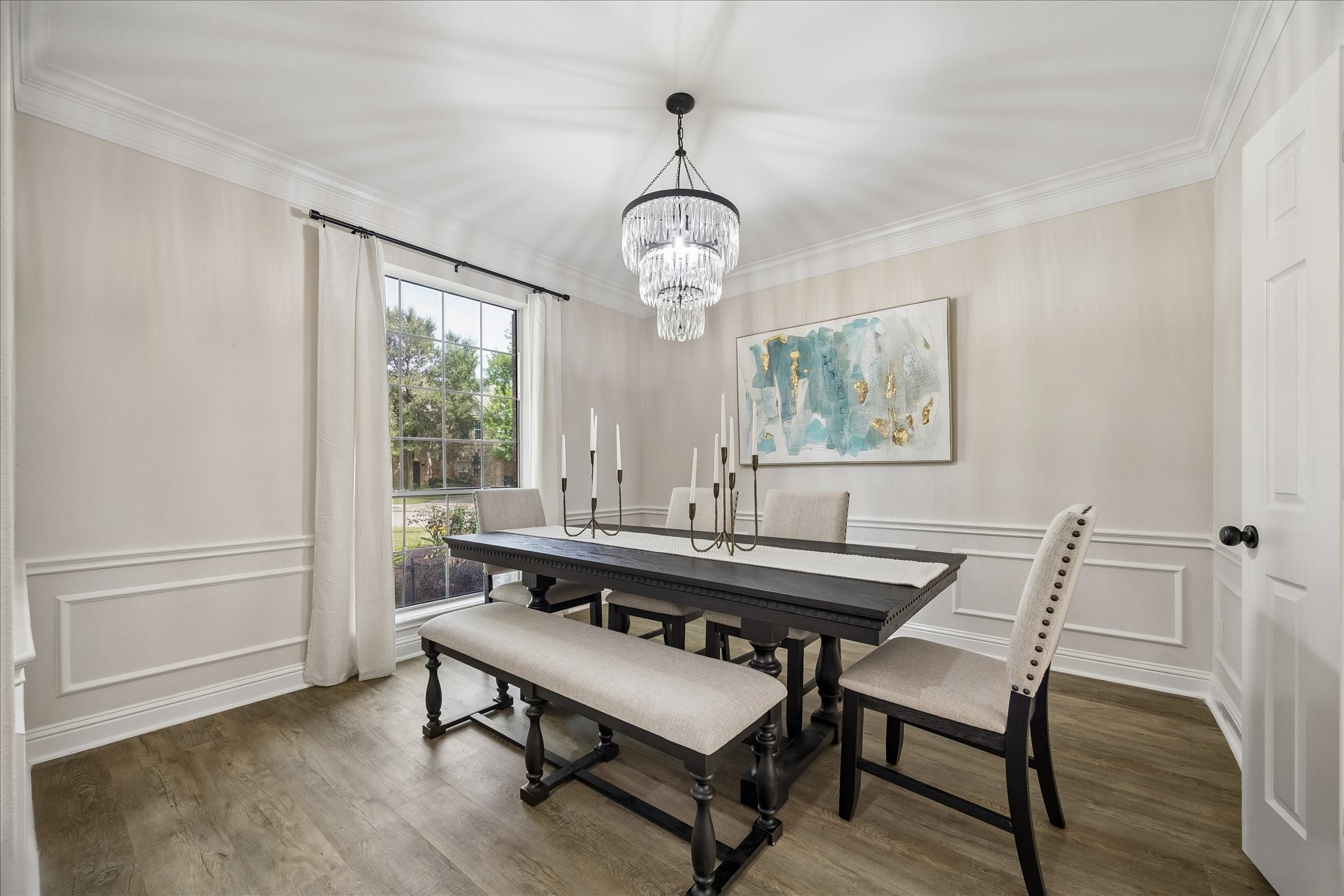 Detailed wainscoting, crown molding, and an elegant chandelier create a refined setting for holiday dinners and special occasions. The dining room offers a classic blend of style and sophistication with passage to the kitchen. Detailed wainscoting, crown molding, and an elegant chandelier create a refined setting for holiday dinners and special occasions. The dining room offers a classic blend of style and sophistication with passage to the kitchen.