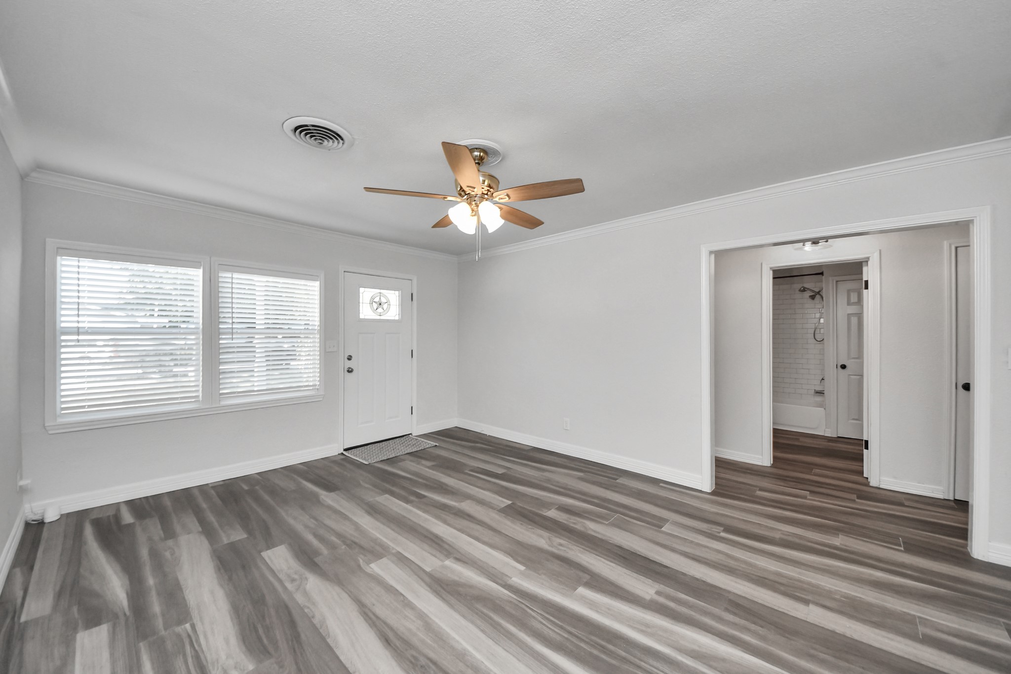 Natural light from the front windows enters the open living room with a view to the hallway that leads to the two, secondary bedrooms and second full bathroom.