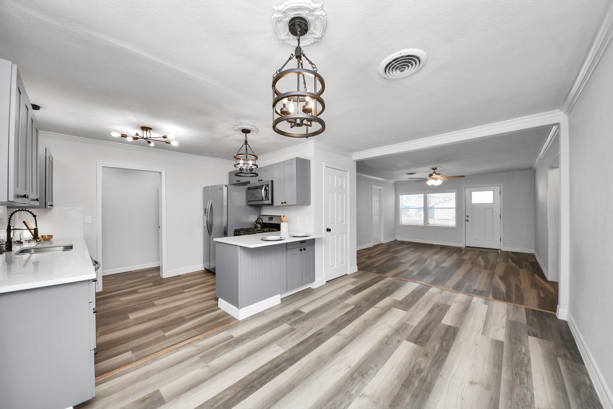 Open Kitchen and Dining Area flowing into the Living Room with Wood-Look Laminate Flooring throughout.