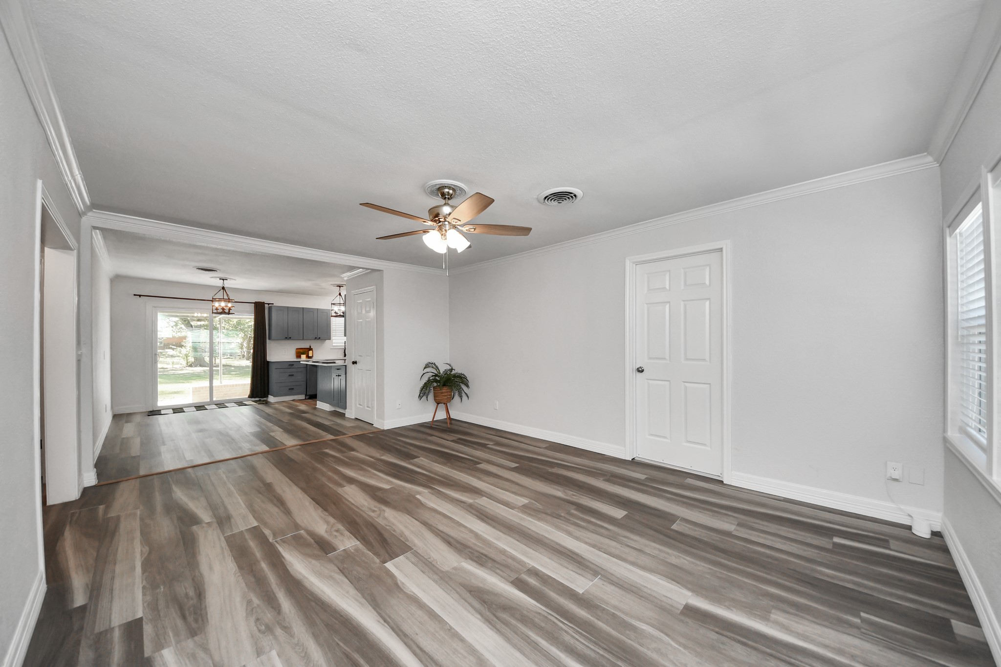 Living Room with Wood-Look Laminate Flooring and open to the dining/kitchen area and easy access to the attached garage. The hallway to the left takes you to the secondary bedrooms and shared bathroom.