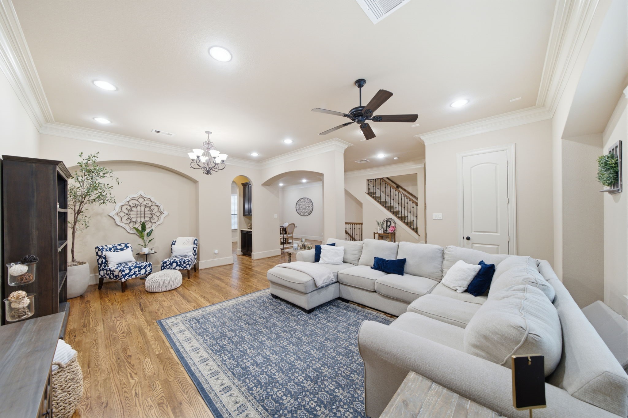 Another angle of the living showing access to the dining and kitchen and beautiful iron staircase.  A closet is behind the door on the right.  Note the triple crown molding throughout this detail filled home.