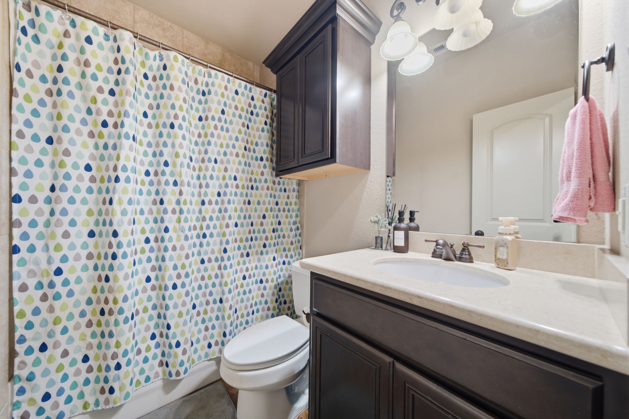 Full guest bathroom on 1st floor with marble countertop and travertine tiled tub/shower.
