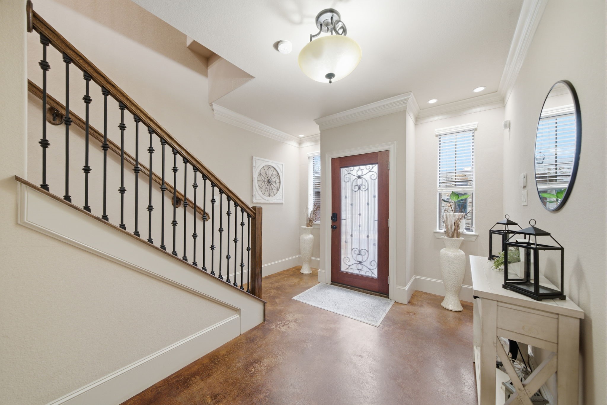Dramatic entryway with glass and iron front door and accent lighting.