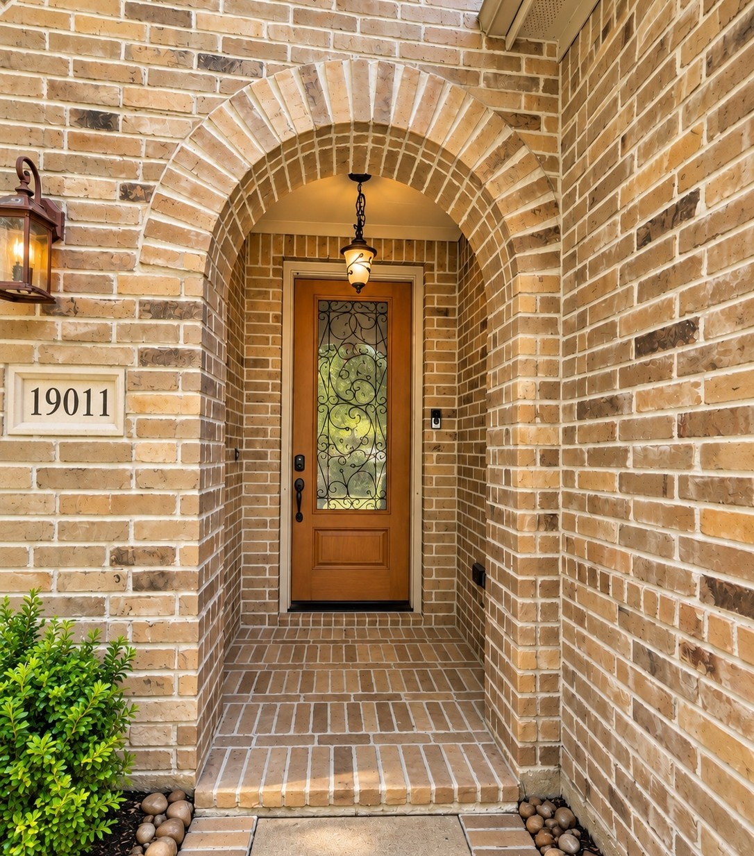 A wood front door with decorative glass and a pendant light give the home a warm, welcoming first impression.