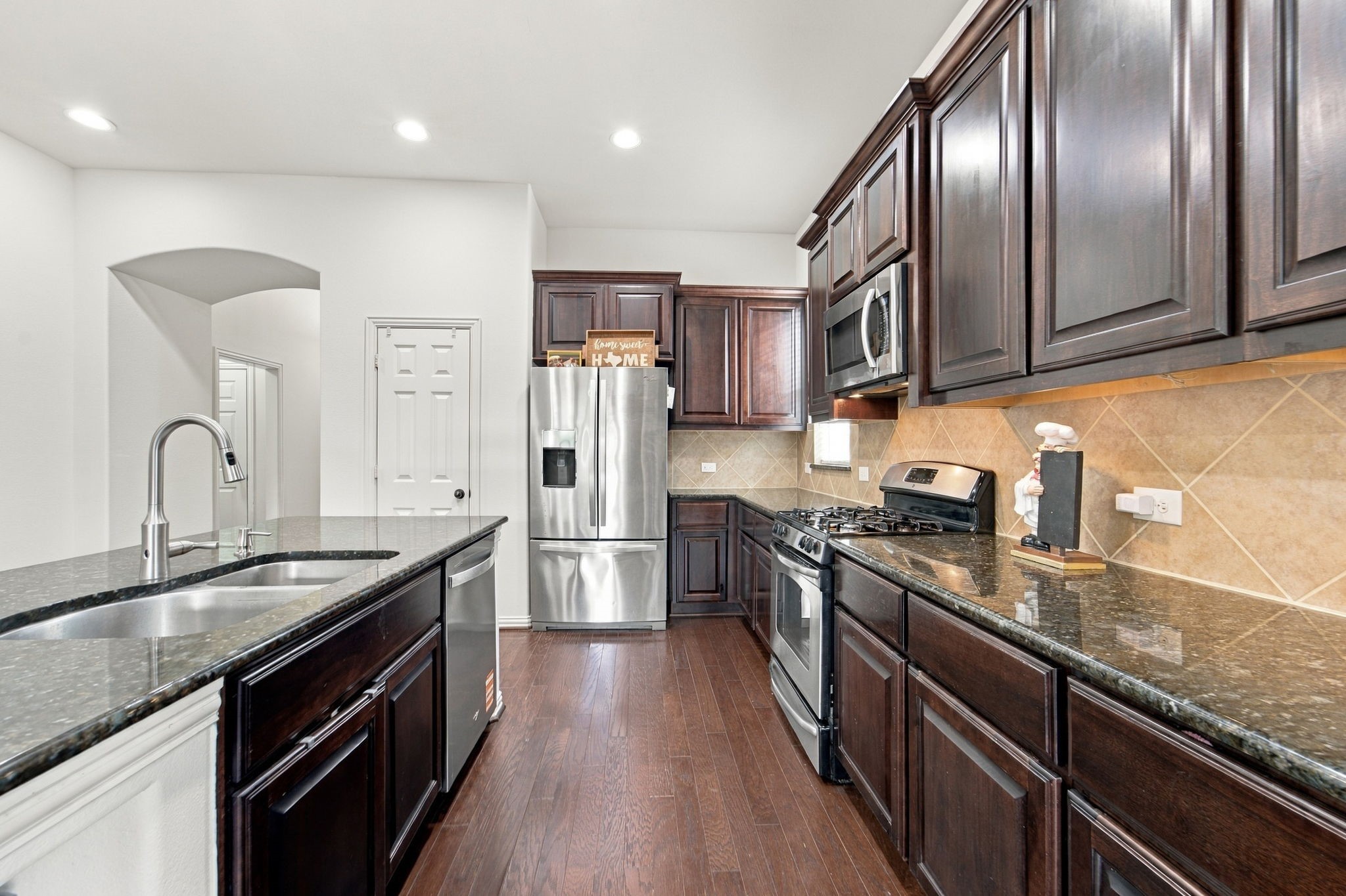 This well-organized kitchen offers generous counter space, tall cabinets, and wood floors that flow into the living area.
