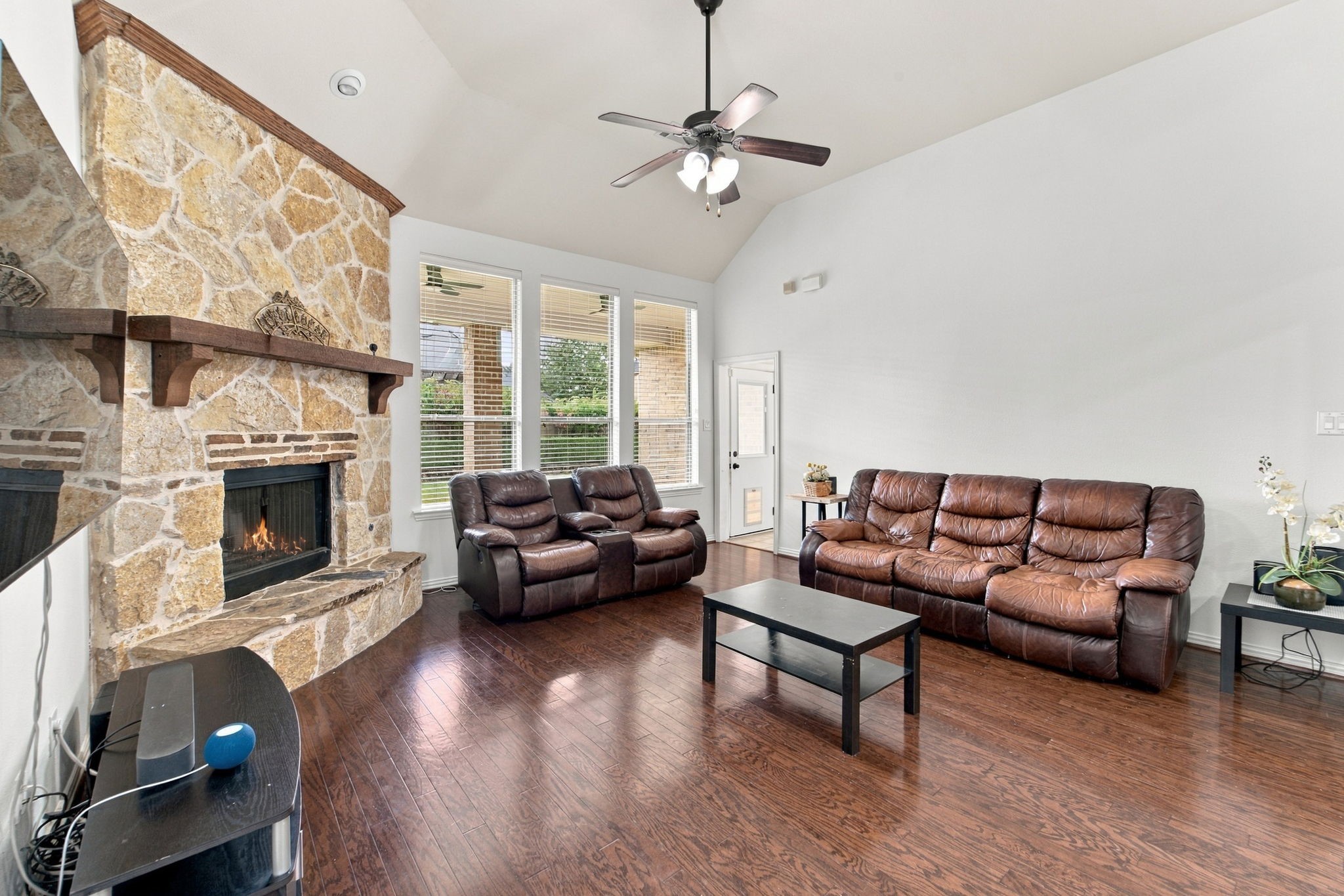 The spacious living room is made for gathering, with a stone fireplace and wood mantel as the focal point.