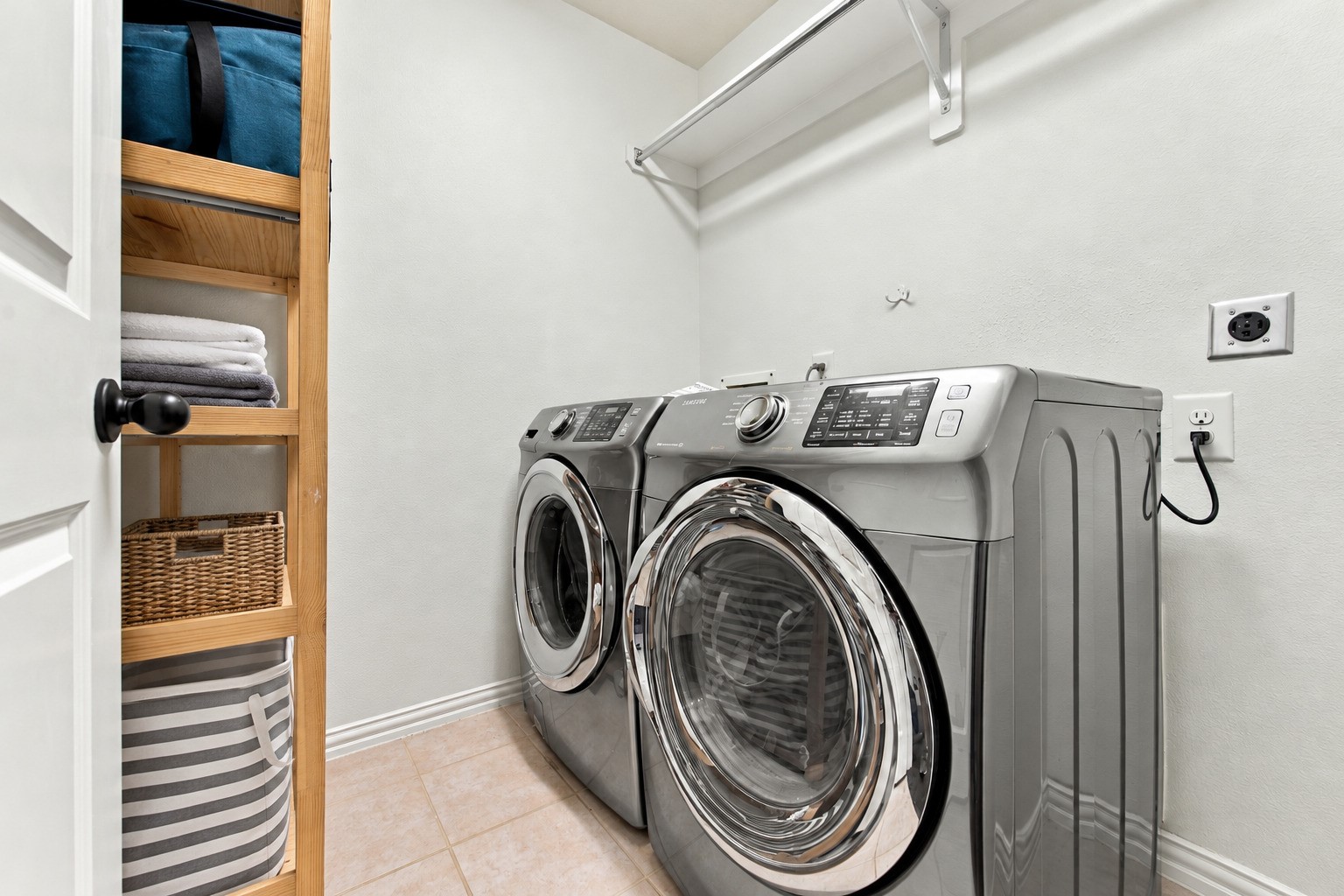 A practical laundry room with space for a full-size washer and dryer, plus a hanging rod for added convenience.