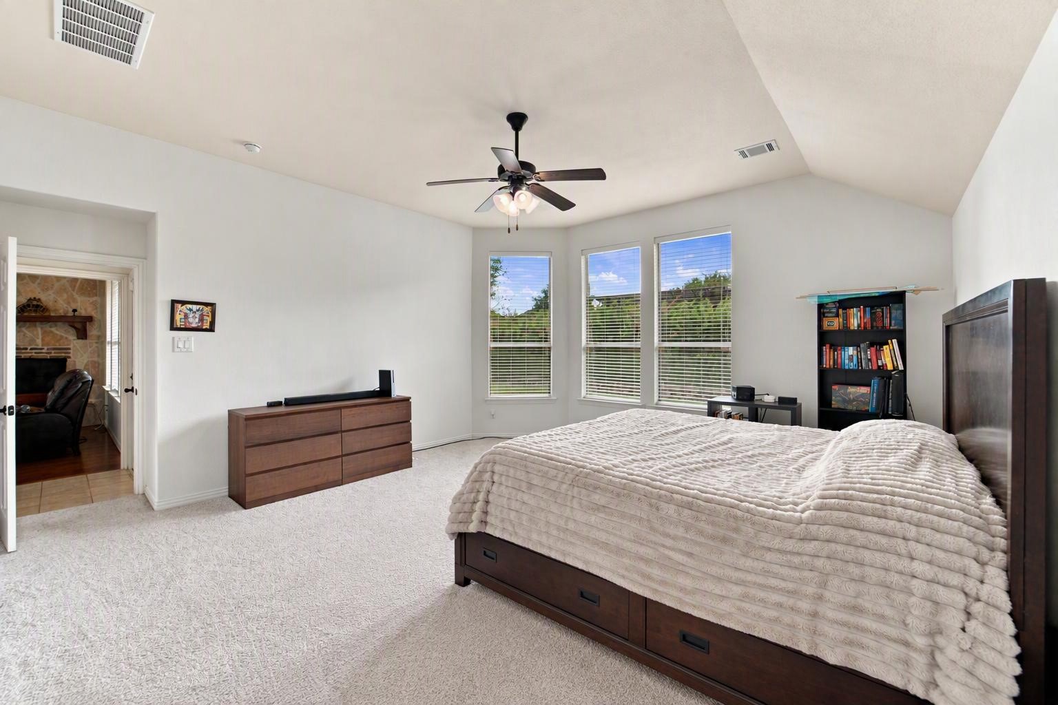 Wake up to green views through a trio of windows in this oversized primary bedroom. A direct connection to the main living area keeps everything convenient on a single level. Edited using AI tools.