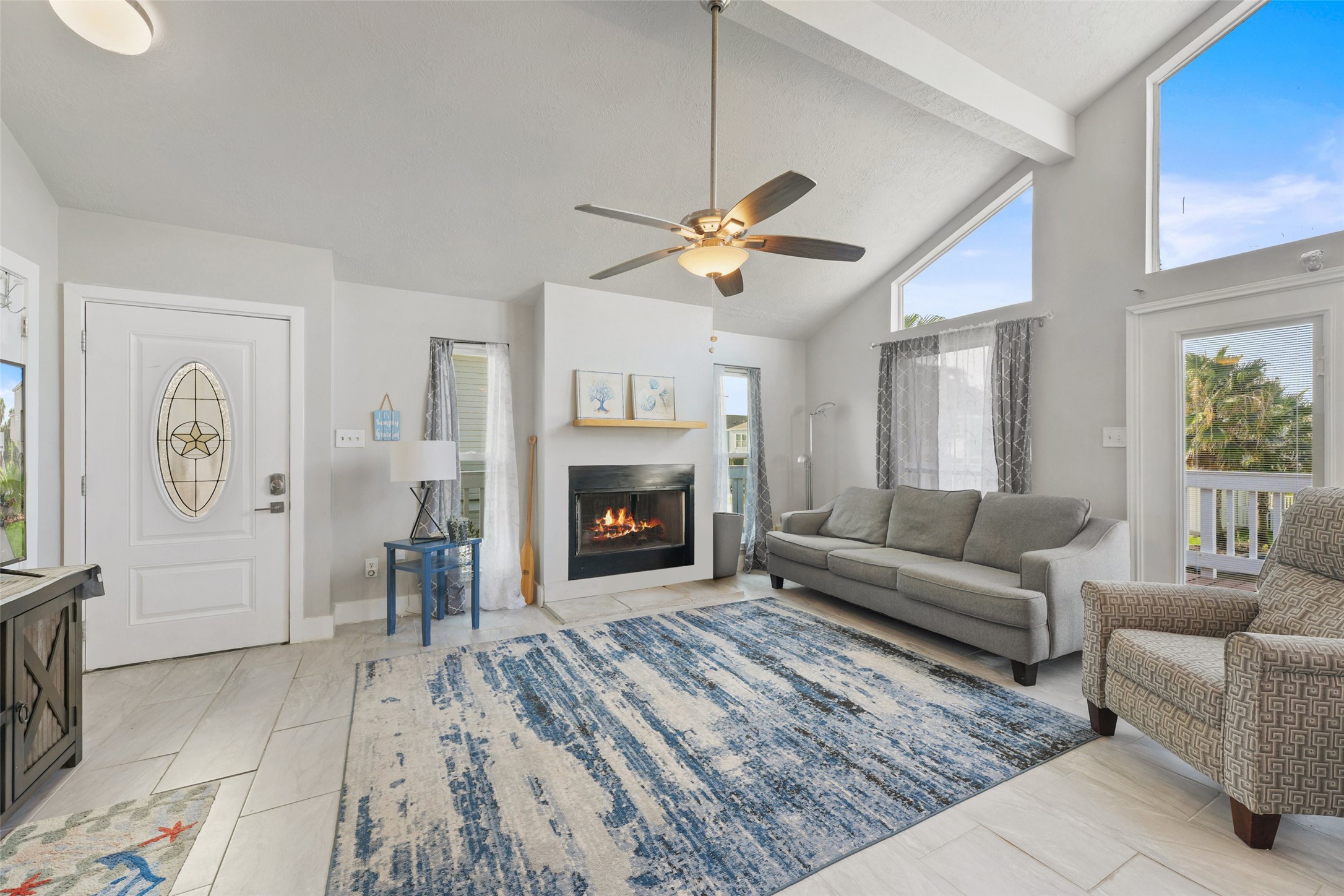 The welcoming living room features tile flooring, a
ceiling fan, high ceilings, cozy fireplace, and a wall
of windows. The welcoming living room features tile flooring, a
ceiling fan, high ceilings, cozy fireplace, and a wall
of windows.