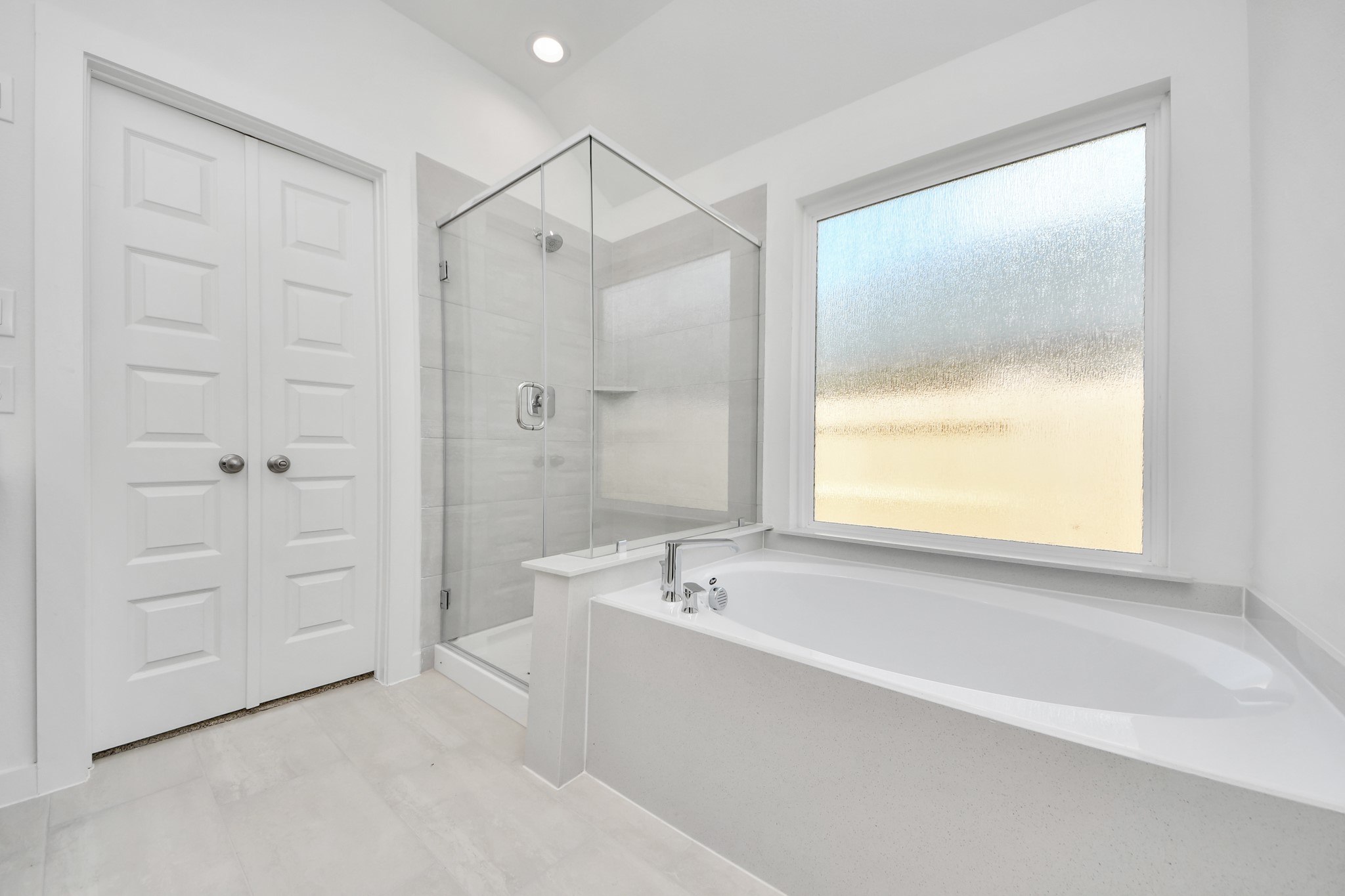 Indulge in a spa-like retreat within the confines of this primary bathroom. Delight in a spacious walk-in shower enveloped in stylish tile surround, unwind in a separate garden tub adorned with custom detailing. Sample photo of completed home with similar floor plan. Actual colors and selections may vary.
