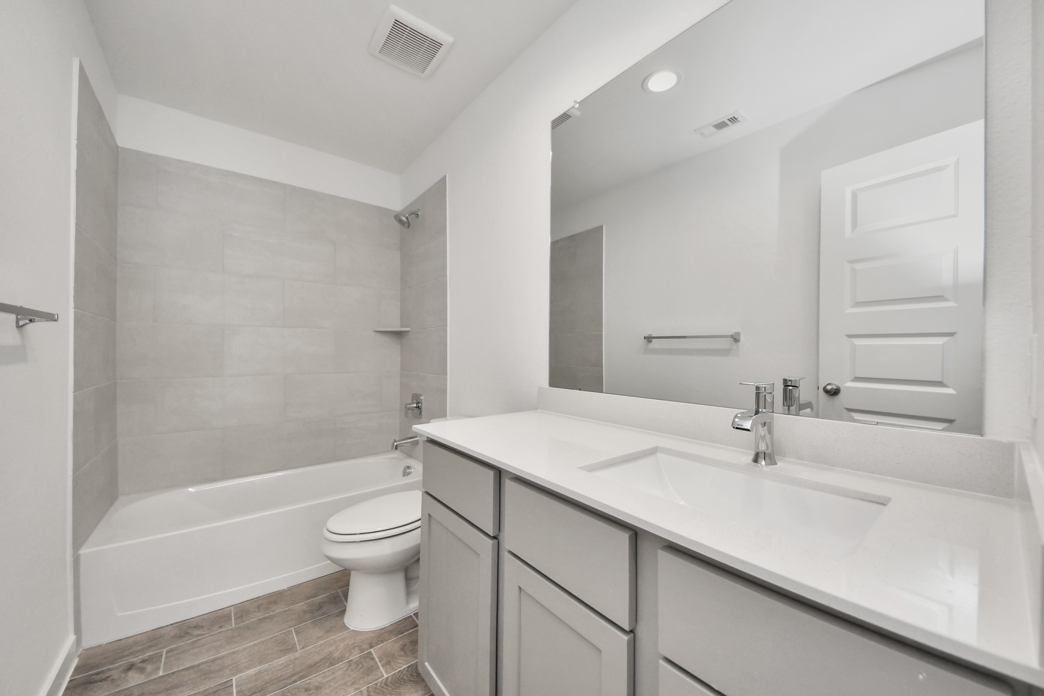 Secondary bath features tile flooring, bath/shower combo with tile surround, light stained wood cabinets, beautiful light countertop. Sample photo of completed home with similar floor plan. Actual colors and selections may vary.