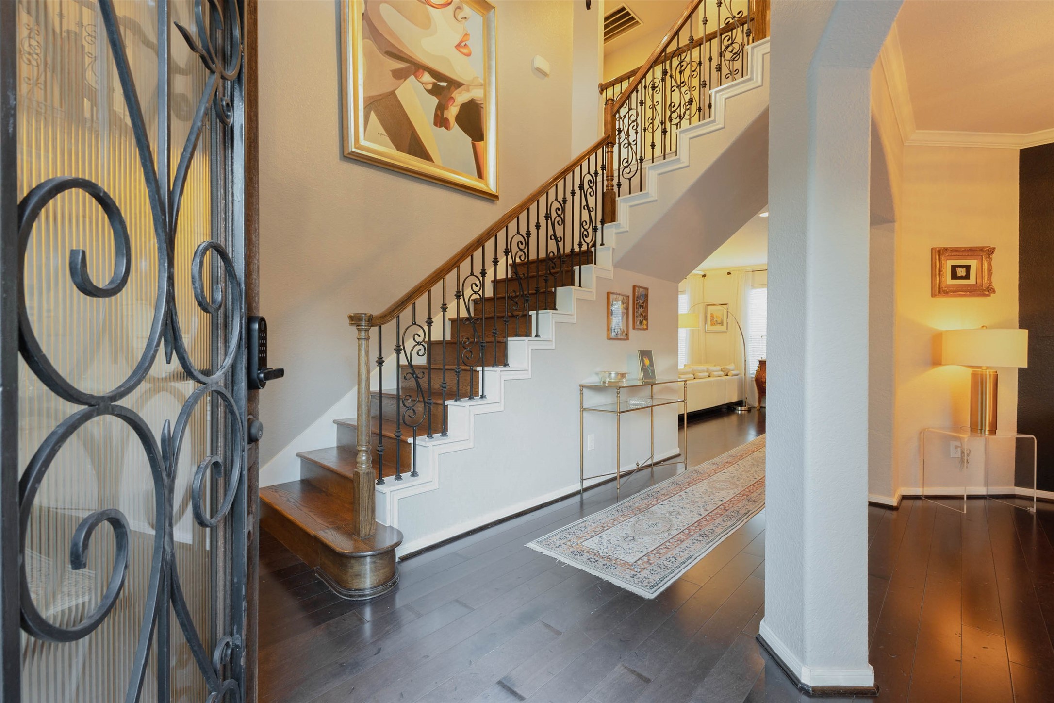 Rich hardwood flooring, intricate wrought-iron detailing, and a sweeping staircase introduce the home's distinctive character with a grand entry.