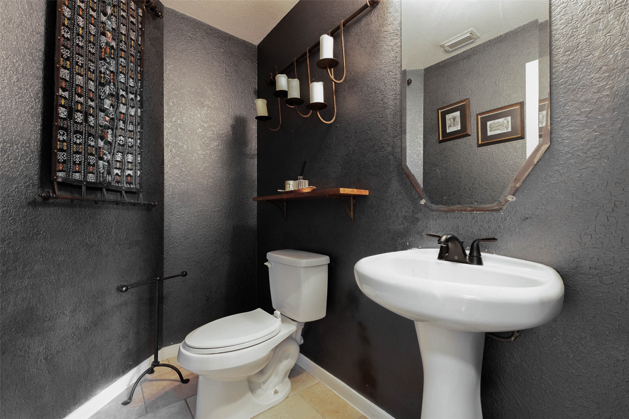 Moody charcoal walls, textured finishes, and sculptural lighting give this powder bath a boutique-inspired edge.