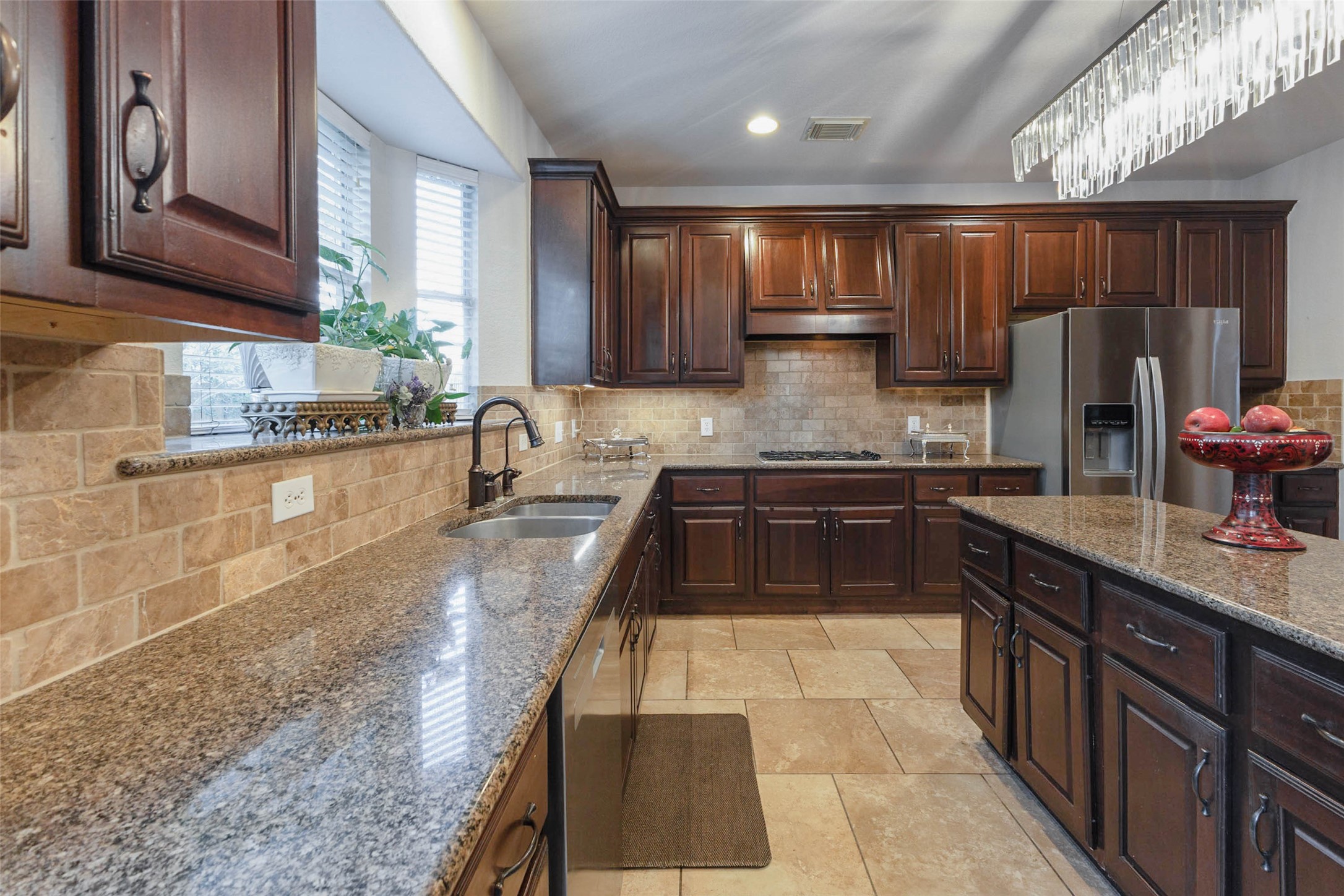 Generous preparation space with expansive granite work surfaces & a neutral stone backsplash in this kitchen.