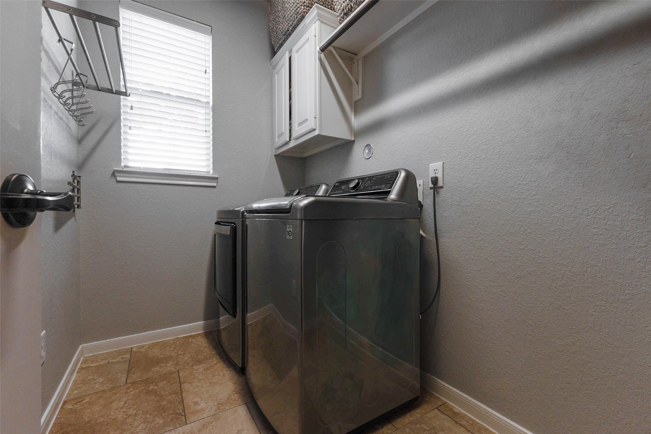 A dedicated laundry room combines overhead cabinetry, hanging space, and natural light for practical everyday convenience.