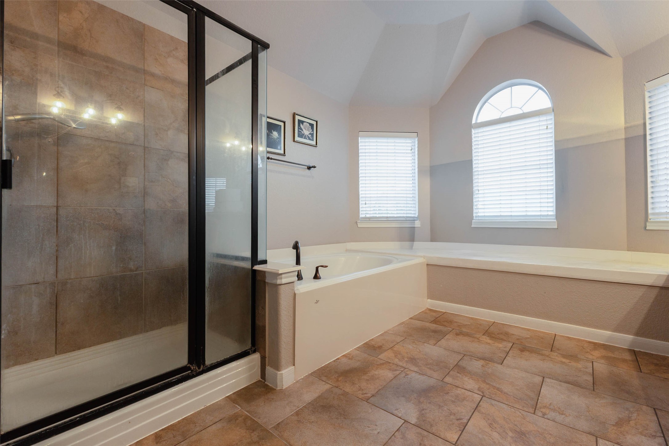 This primary bath features a soaking tub, separate glass-enclosed shower & inviting sitting ledge.