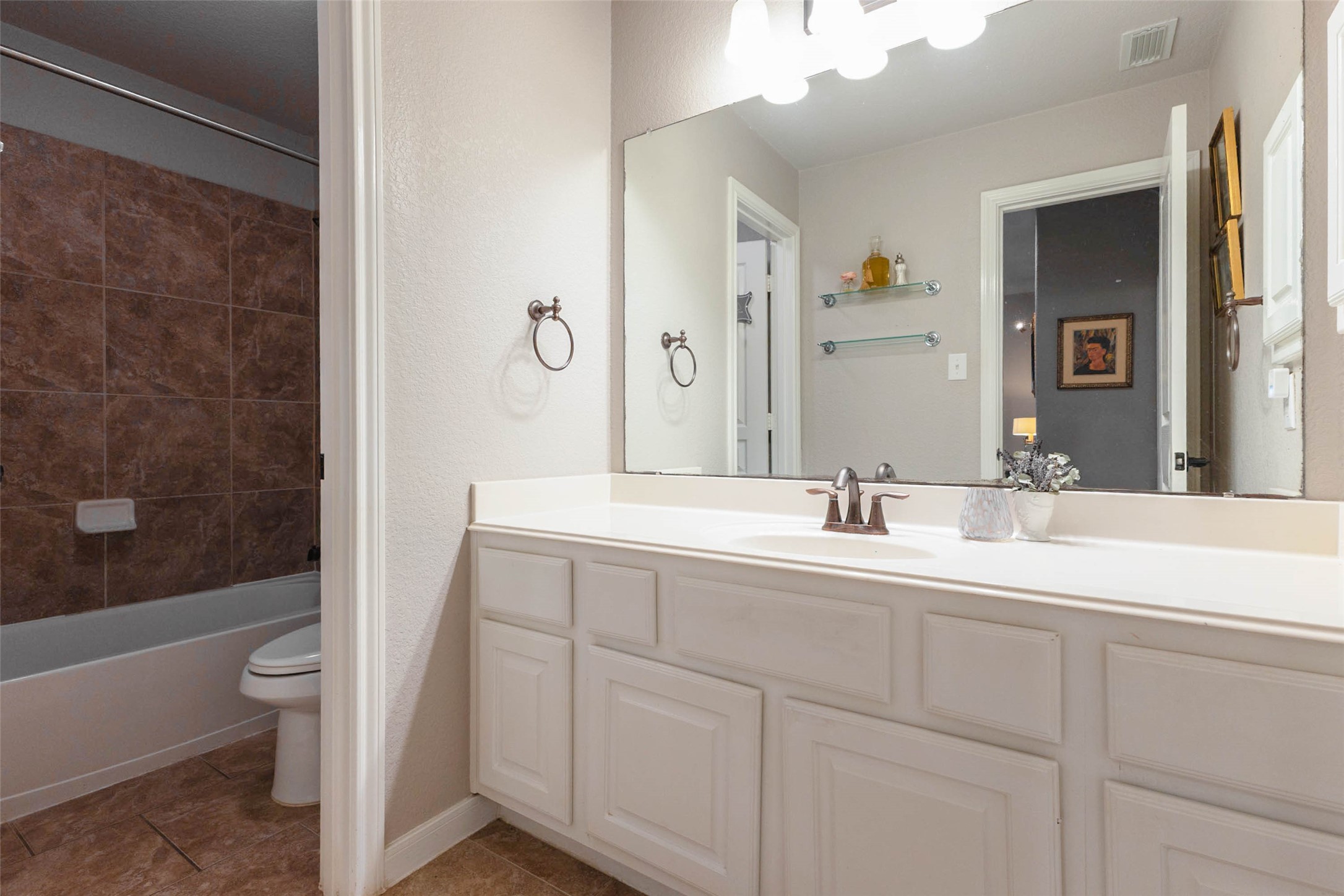 A well appointed secondary bathroom features a spacious vanity and a tiled tub-and-shower combination.