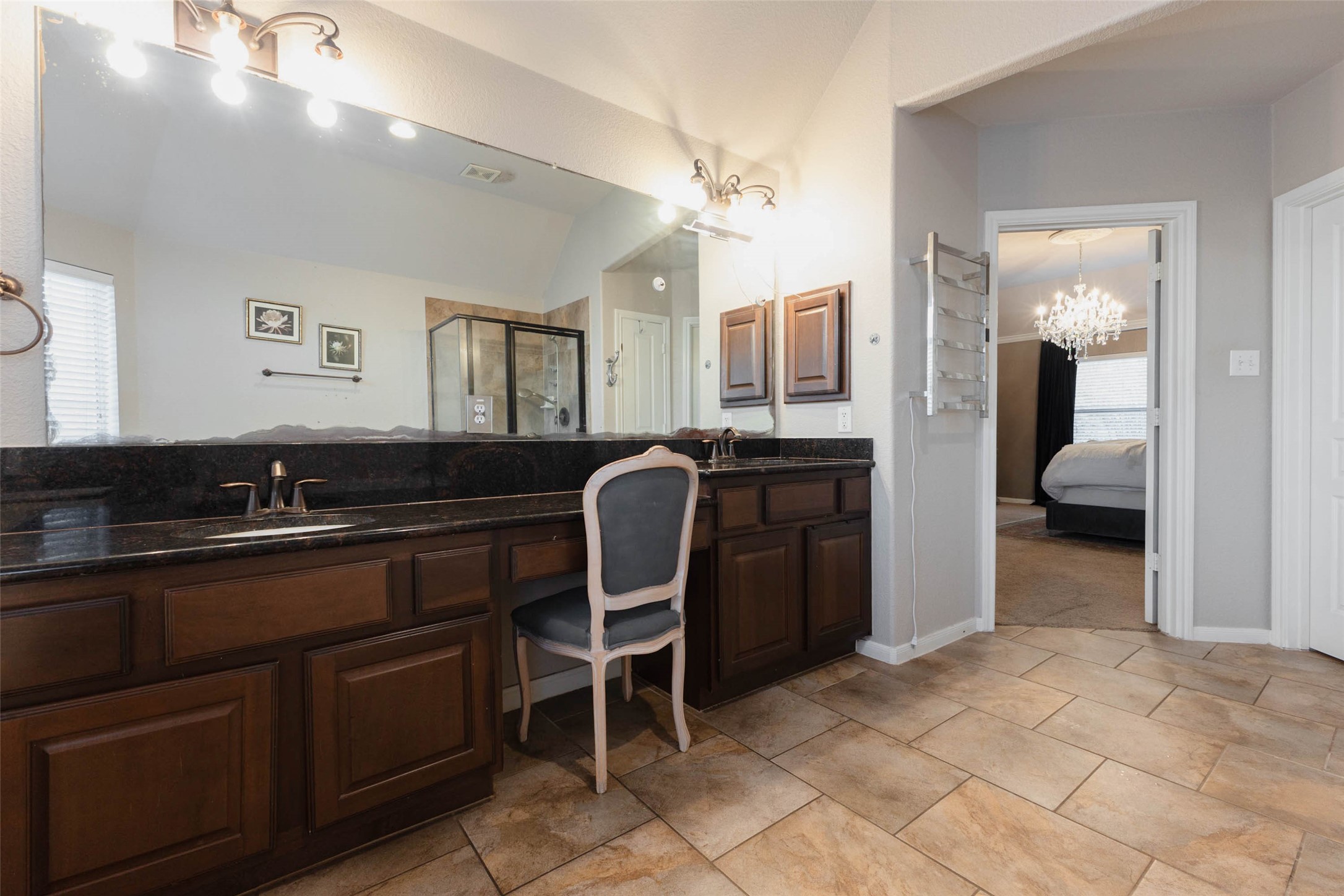 A double-sink vanity pairs dark granite countertops with rich wood cabinetry & ample storage.