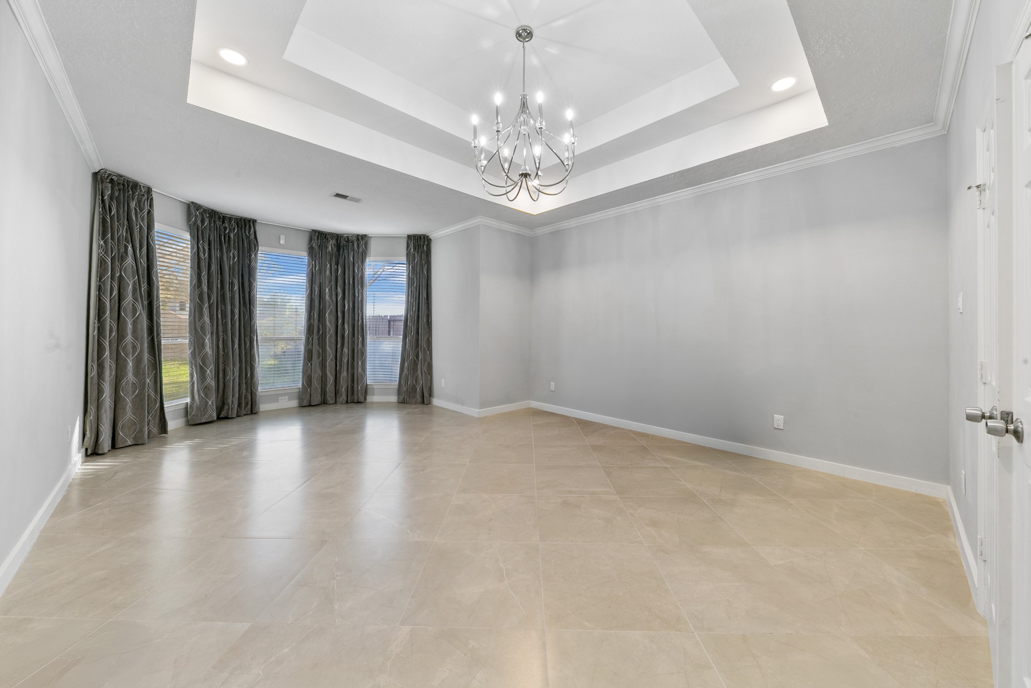 Large Master bedroom with beautiful tray ceiling and chandelier. .