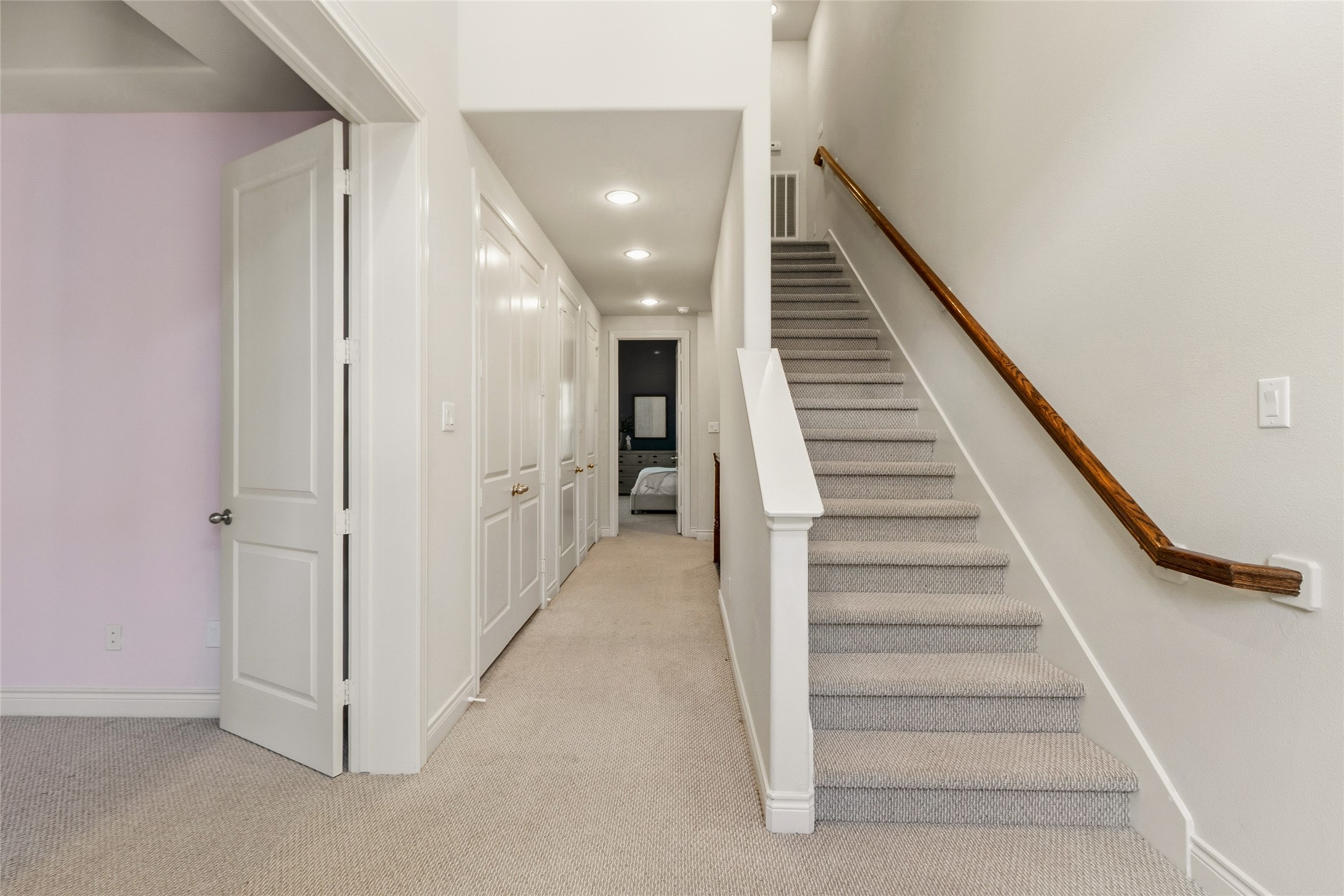 Bright second-floor landing with recessed lighting, plush carpet, and a staircase leading up to the third level.