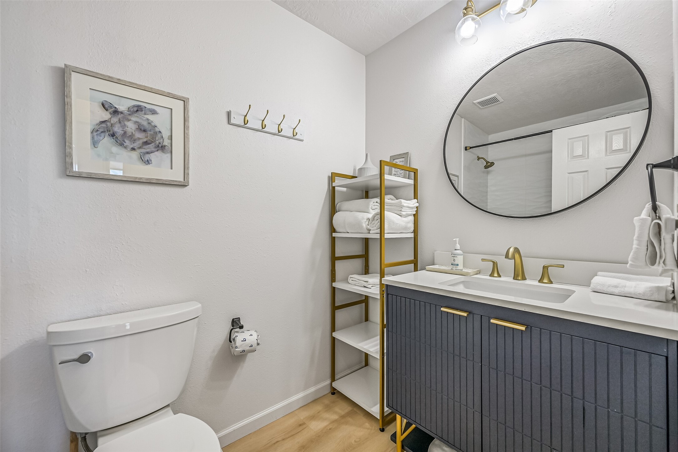 The renovated guest bathroom hosts a tub/shower combo with gold accents throughout.