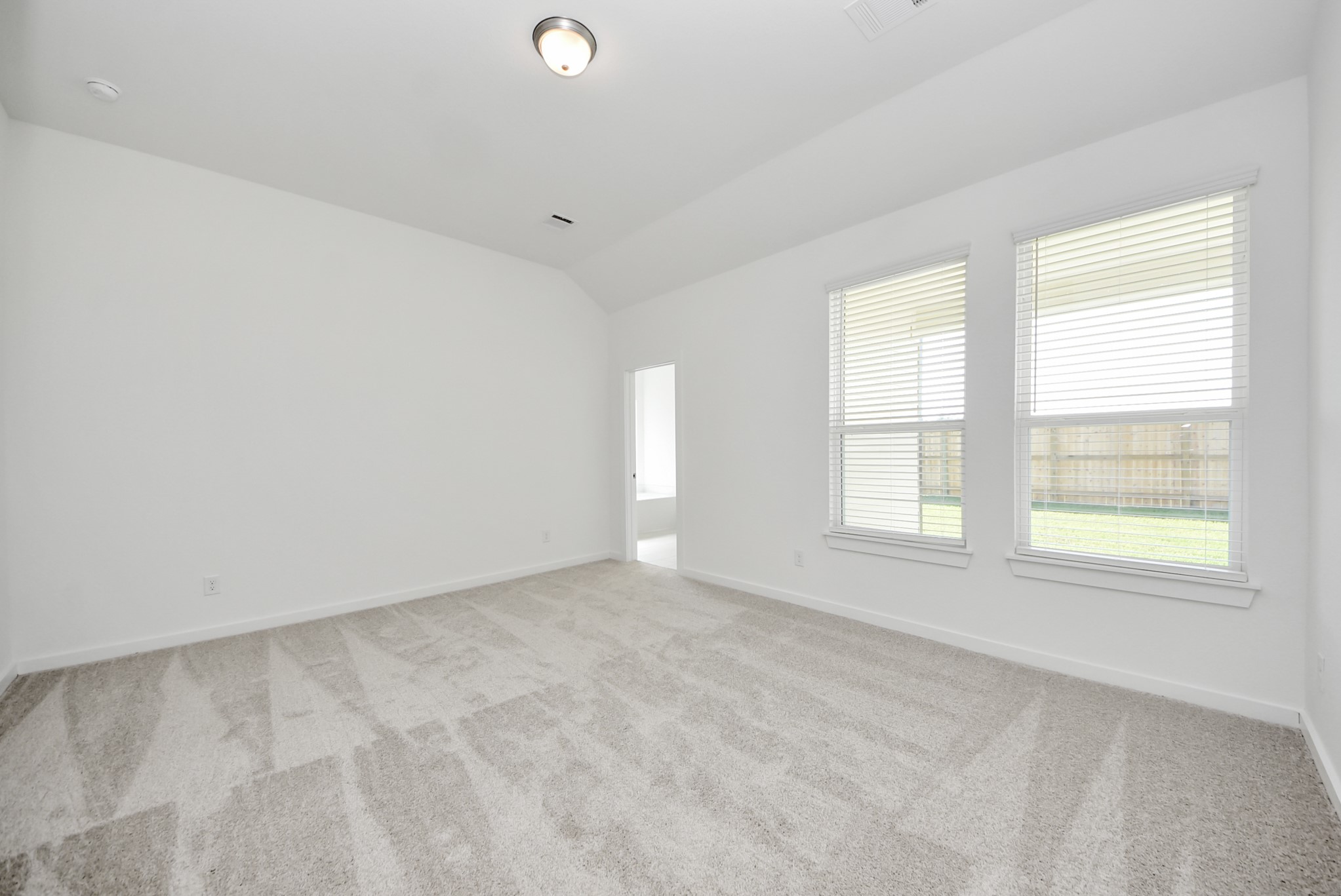 Retreat to the luxurious primary suite, your perfect escape for unwinding after a long day. Located on the first floor, this spacious room features plush carpeting, calming paint tones, high ceilings, and large windows with privacy blinds.