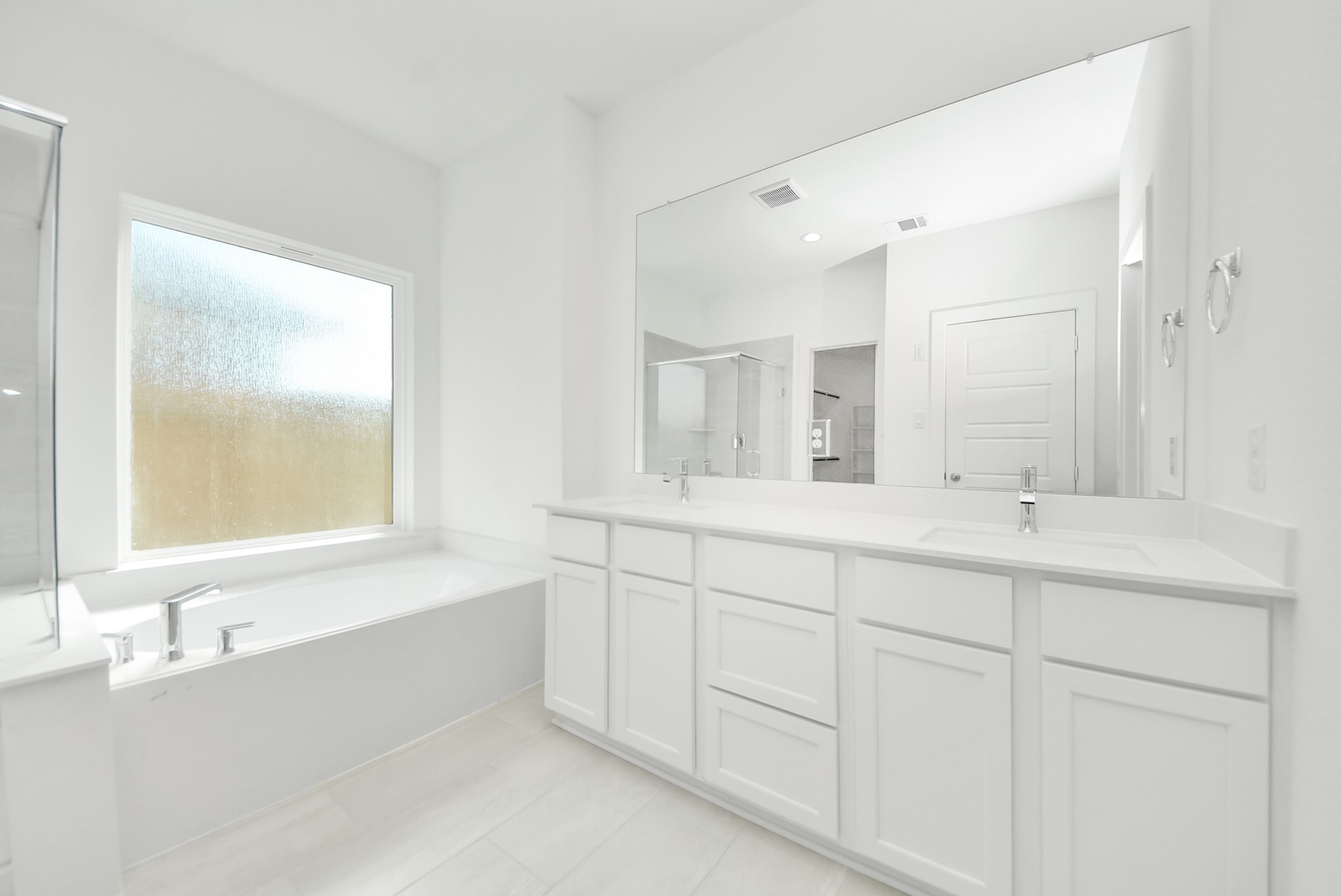 Elevate your daily routine at the elegant vanity, now equipped with double sinks, light countertops, modern hardware, and beautiful recessed lights.