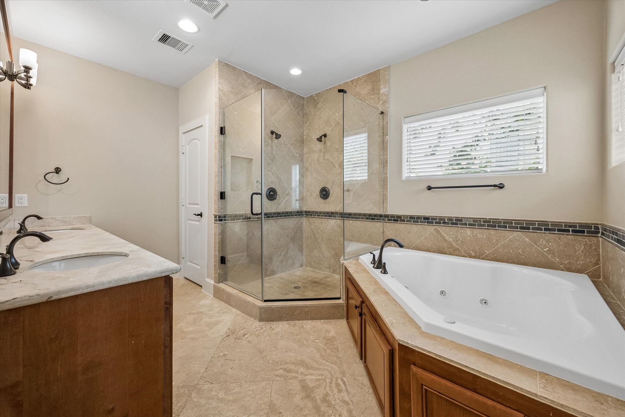 The primary bath features dual sinks, a jetted soaking tub and glass encased shower with dual shower heads.
