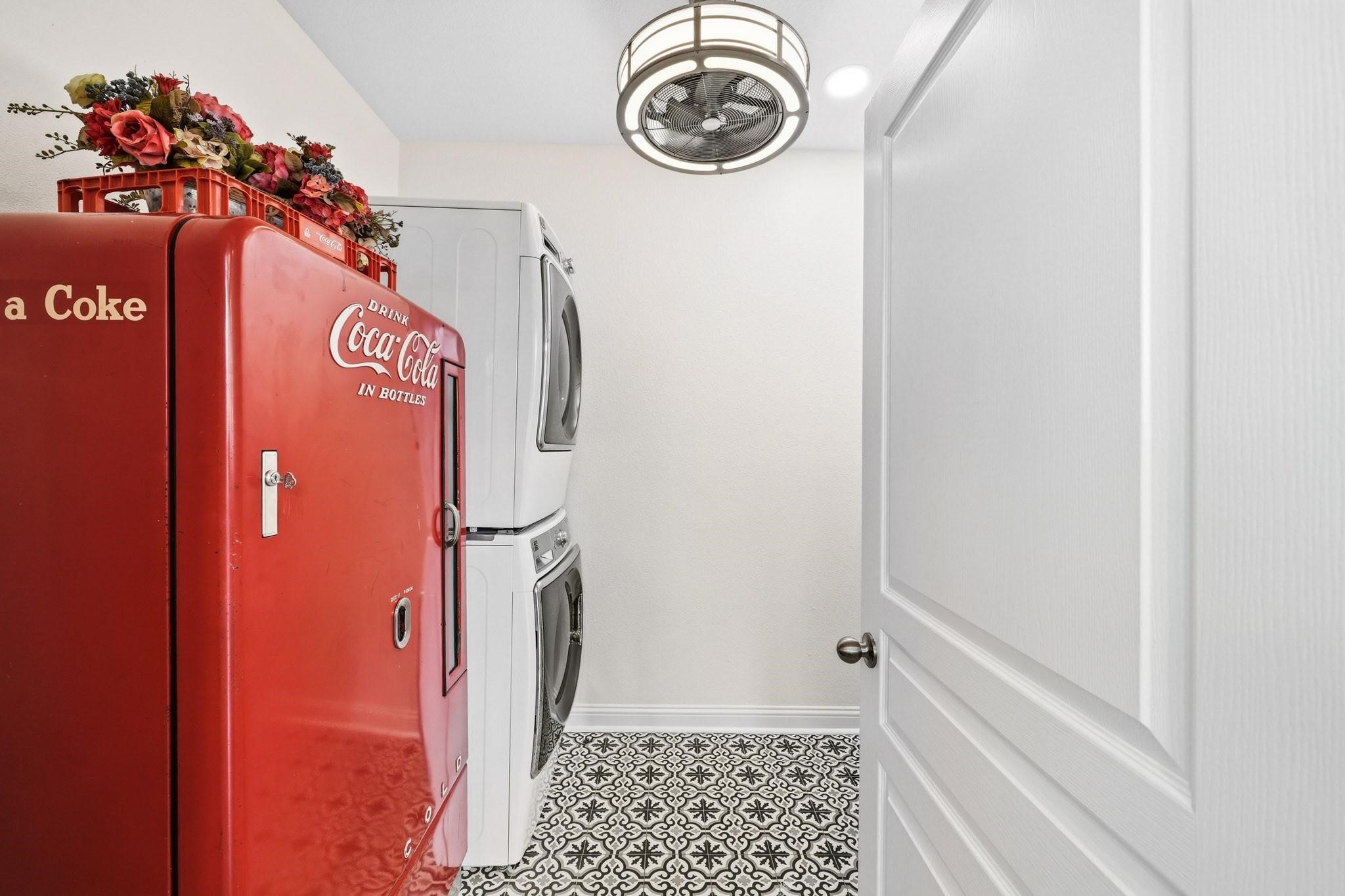 The spacious utility room combines style and function with decorative tile flooring, abundant built-in cabinetry, and a full-size Kenmore front-load washer and dryer.