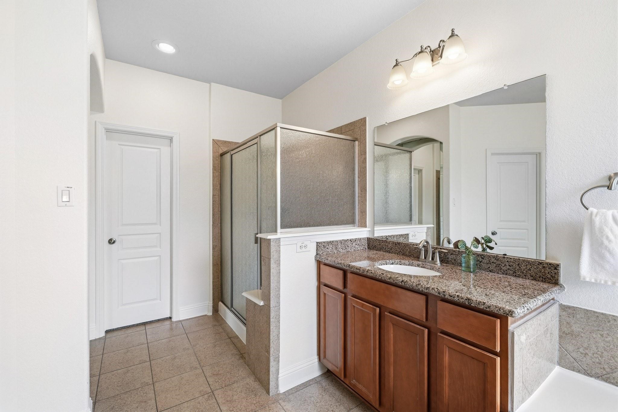 The spacious walk-in shower features a built-in bench and elegant tile surround, creating a relaxing retreat, while the oversized closet with double hanging rods and dedicated shoe storage keeps everything impeccably organized.