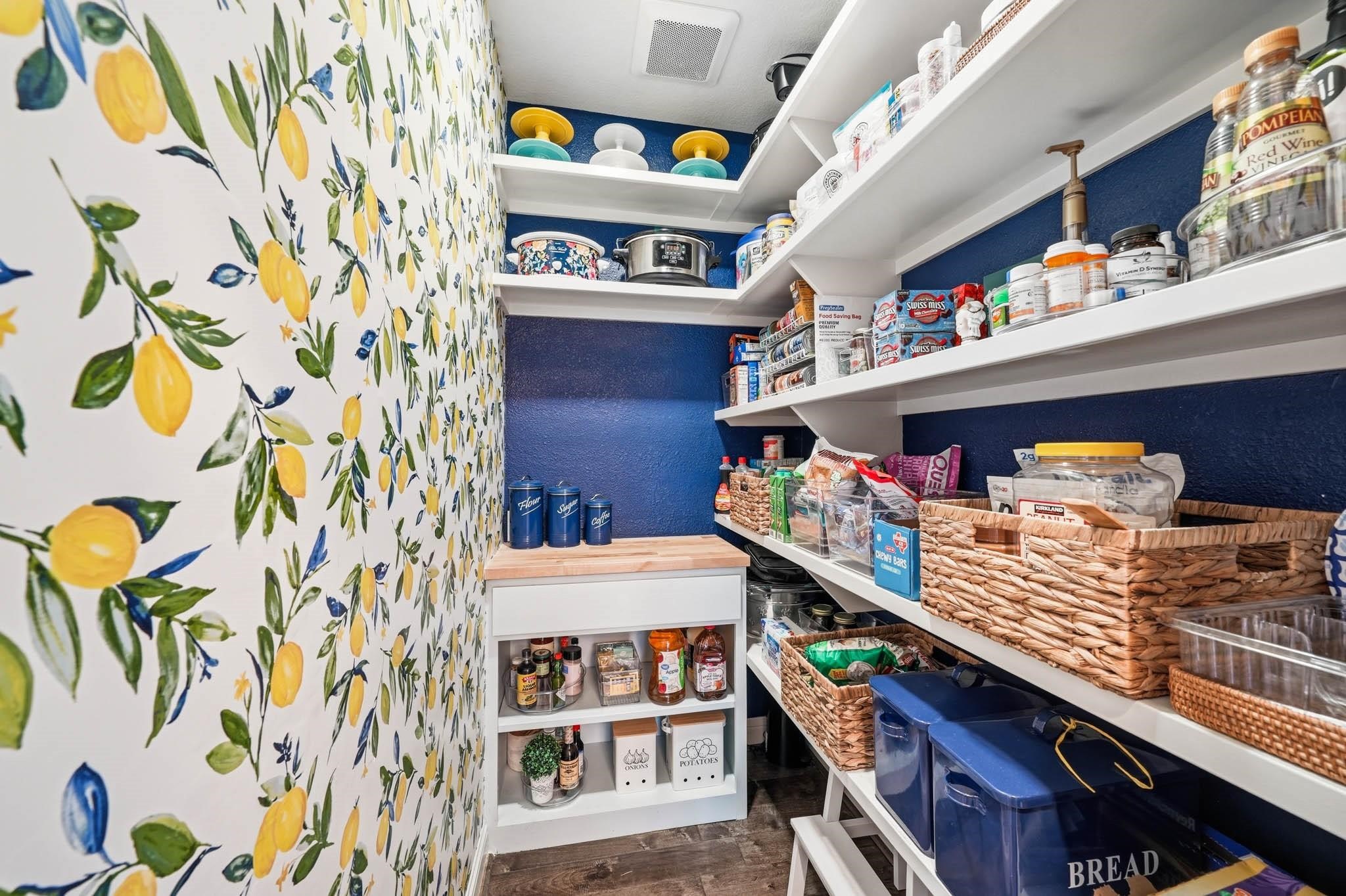 The expansive pantry with bright and cheery wallpaper combines practicality with luxury, offering abundant storage that keeps everything organized and effortlessly accessible.