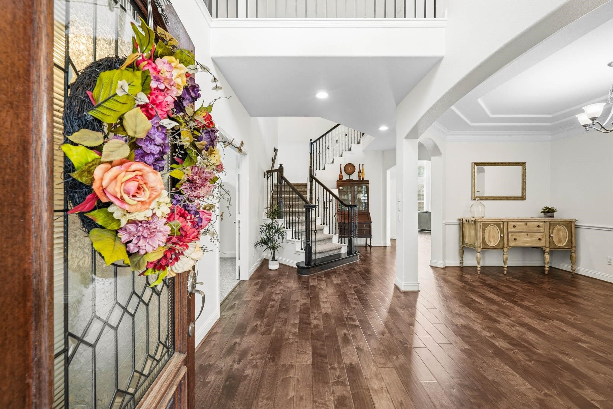 A grand two-story foyer with rich hardwood floors creates a striking first impression, seamlessly connecting to the dining room through an elegant arched opening. A grand two-story foyer with rich hardwood floors creates a striking first impression, seamlessly connecting to the dining room through an elegant arched opening.