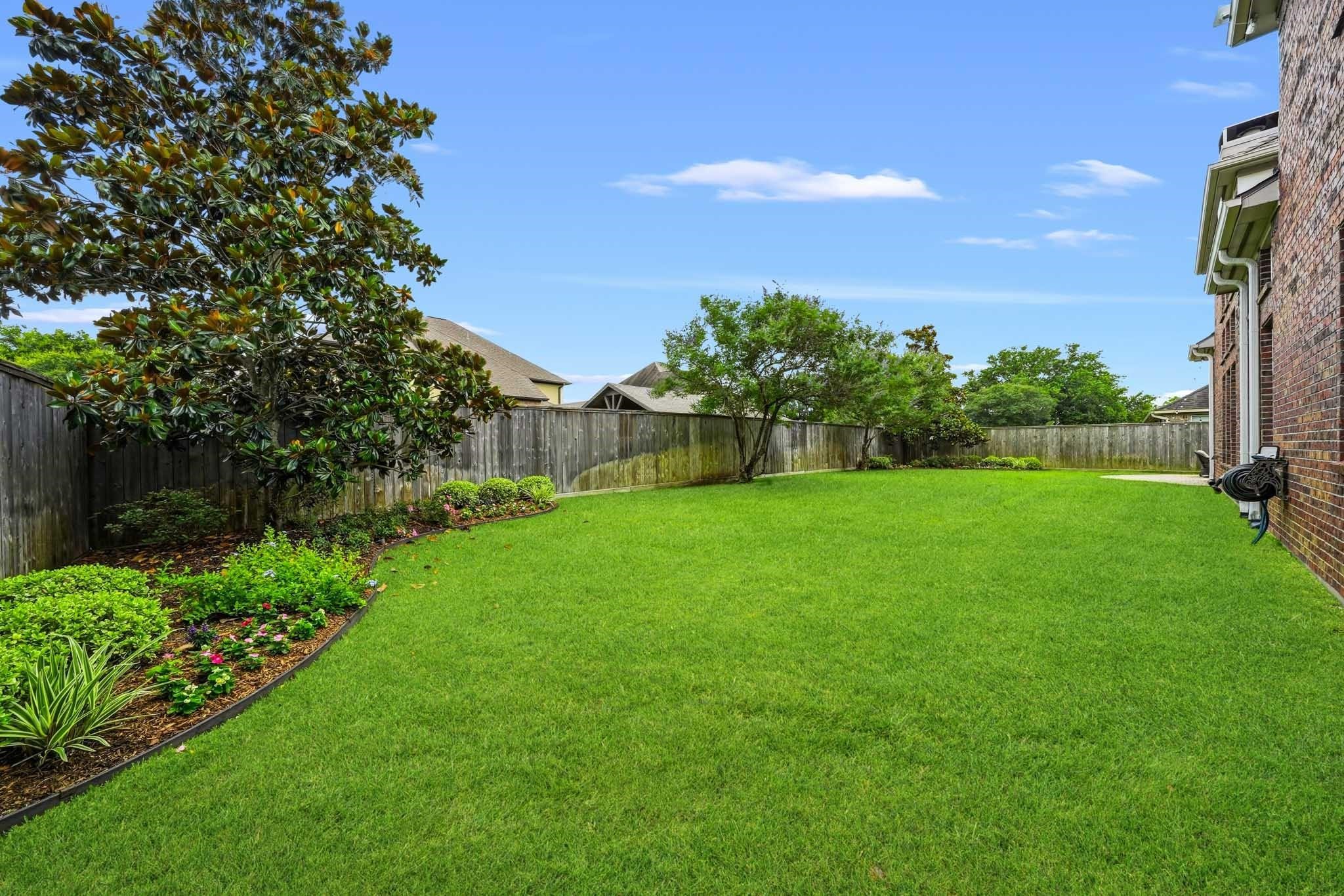 A beautifully maintained backyard retreat awaits, complete with mature trees, sweeping lawn space, and plenty of room for pets to roam.