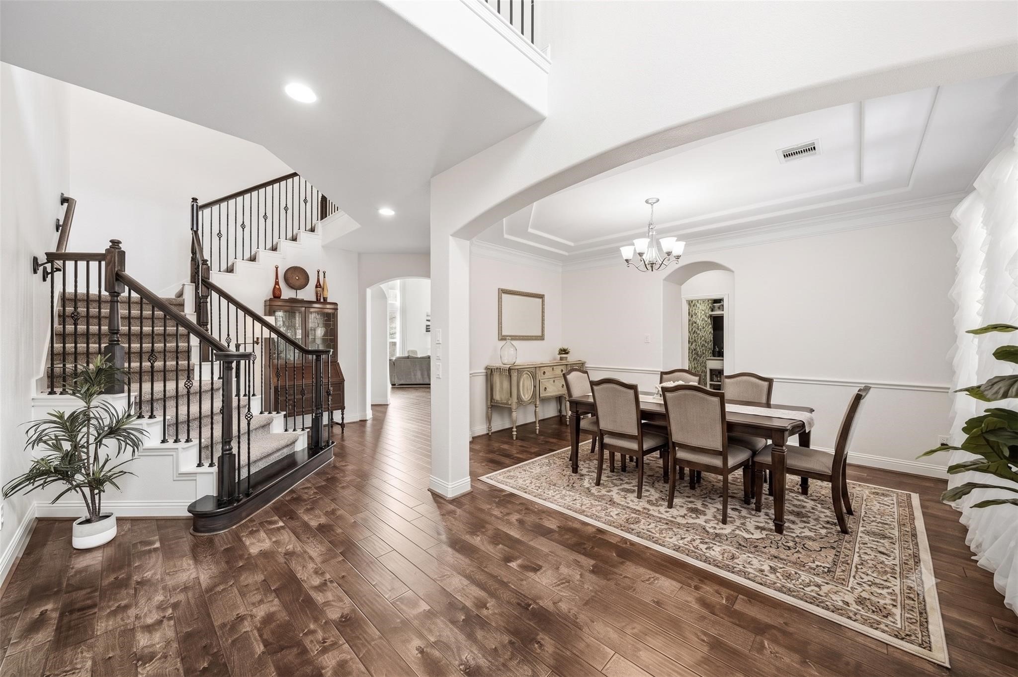 The formal dining room exudes classic elegance with double crown molding and has a beautifully appointed chandelier as its centerpiece. The arched doorway leads to the pantry and Butler's pantry.The wrought iron staircase leads to the upstairs. This photo has been virtually staged. The formal dining room exudes classic elegance with double crown molding and has a beautifully appointed chandelier as its centerpiece. The arched doorway leads to the pantry and Butler's pantry.The wrought iron staircase leads to the upstairs. This photo has been virtually staged.