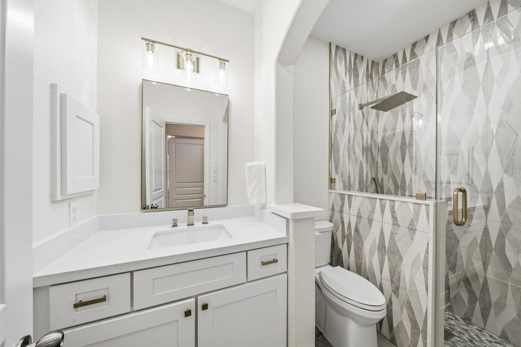 The third bath has been beautifully reimagined with oversized 12x24 tile floors, Quartz counters, and a stunning floor-to-ceiling tiled shower featuring a rain head and separate spray wand for a spa-inspired experience.