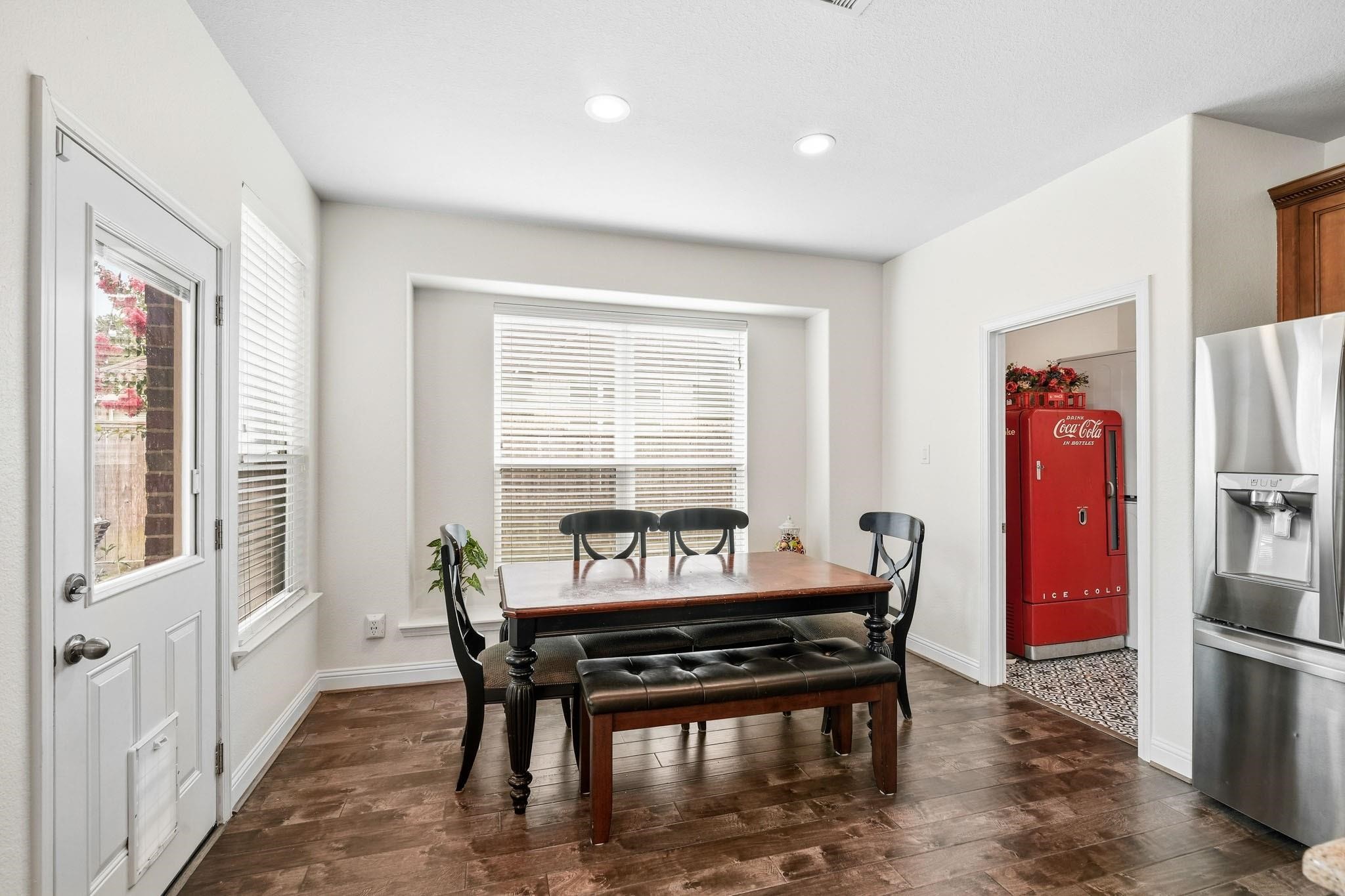 Bathed in natural light, this cheerful breakfast nook features a cozy window seat and seamless access to the patio through a glass door, blending indoor comfort with outdoor enjoyment. The laundry room sits to the right.