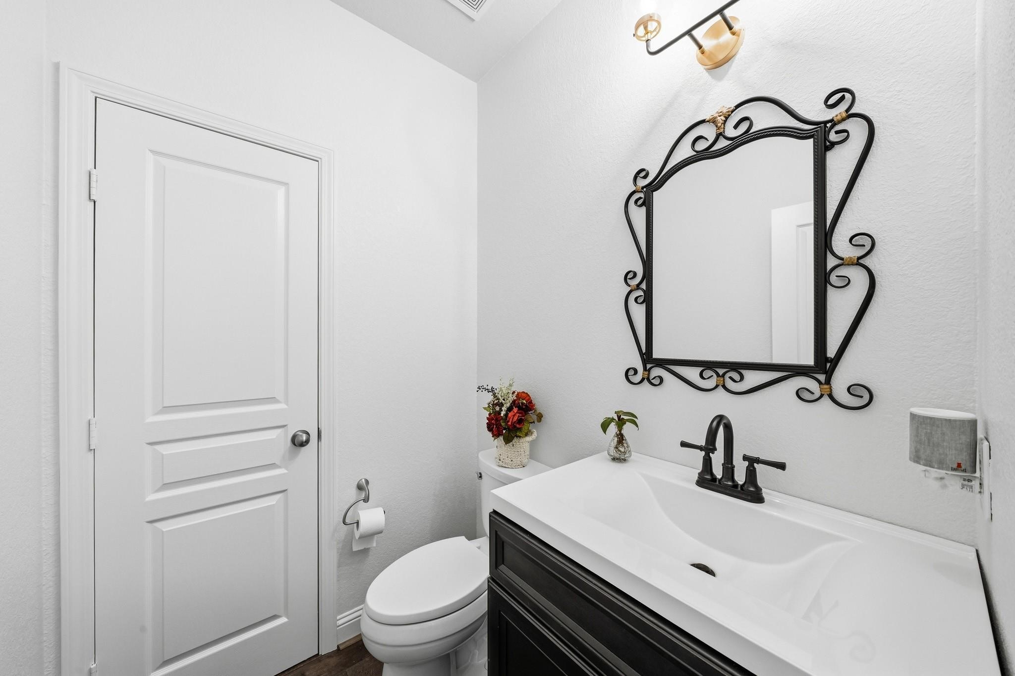 Designer finishes elevate this stylish powder room, where a furniture-style vanity, statement mirror, and curated lighting create a sophisticated guest experience.