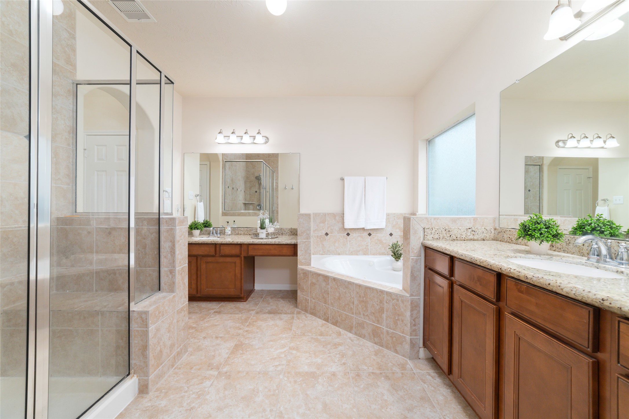 The luxurious primary en-suite bath features separate vanities, a soaking/jetted tub and an oversized, separate shower.