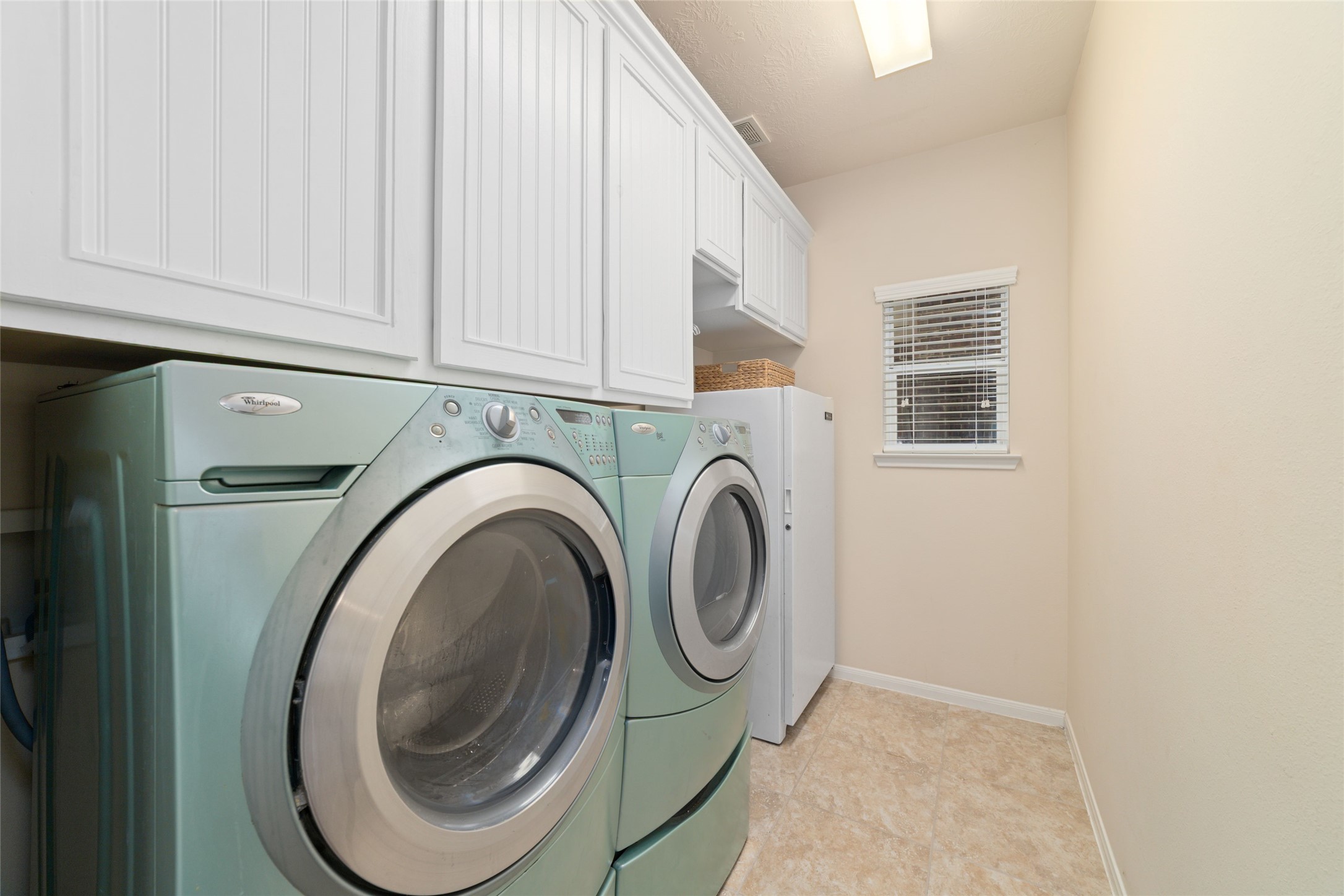 Large laundry room with plenty of upper cabinet storage space.
