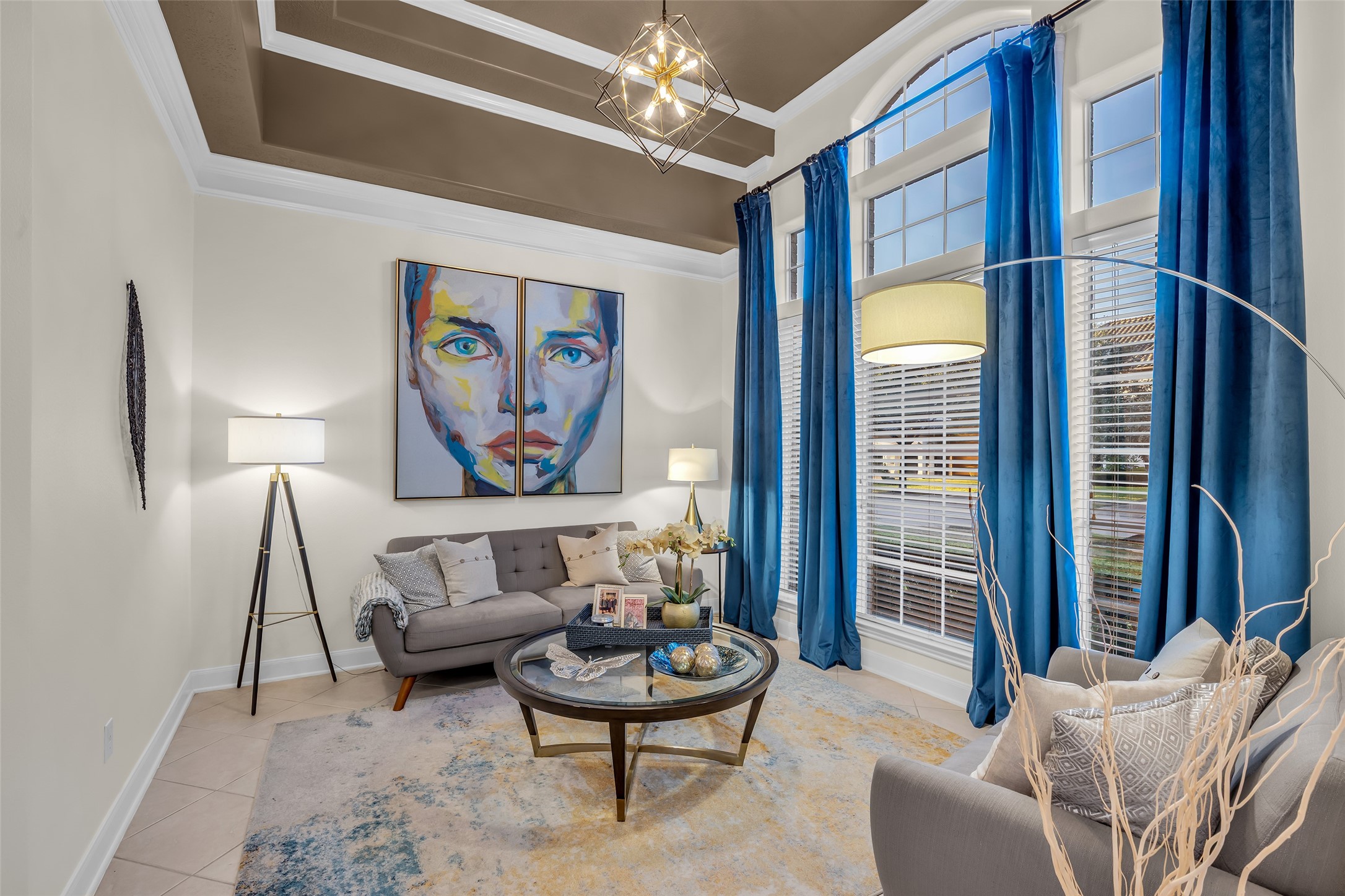 A stylish formal living room features high ceilings, large windows and a contemporary light fixture.