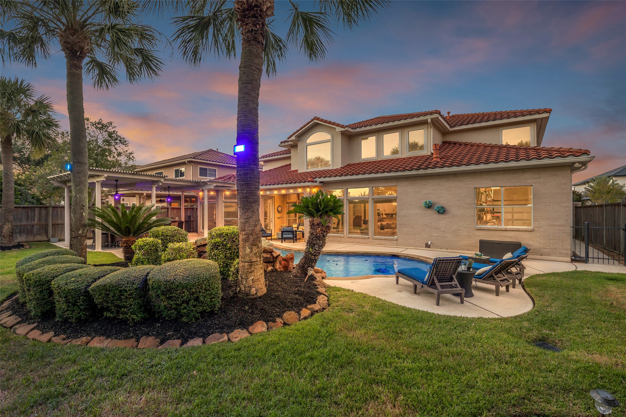 Lush tropical landscaping with palms, sculpted hedges and installed landscape lighting for beautiful evenings outdoors