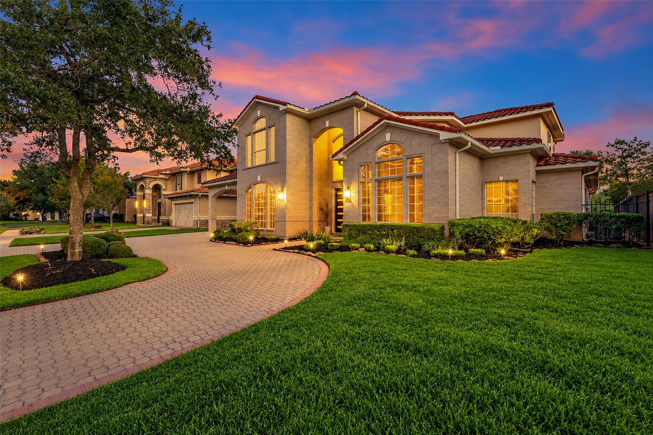The circular paver driveway leads to the porte-cochre and a modern glass garage door.