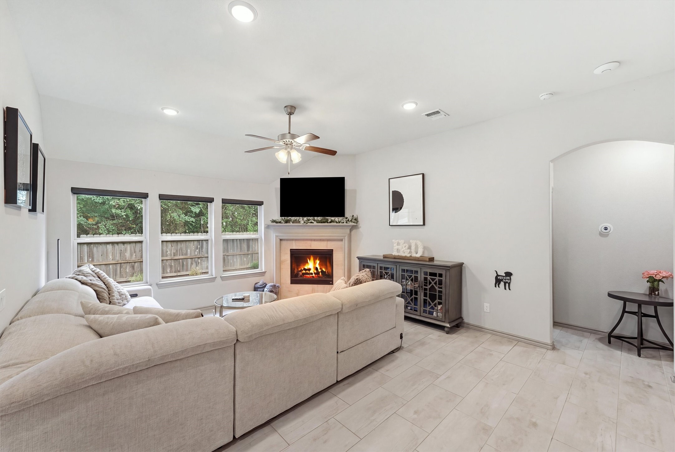 Spacious living room featuring a cozy fireplace, abundant natural light, and large windows overlooking the backyard.