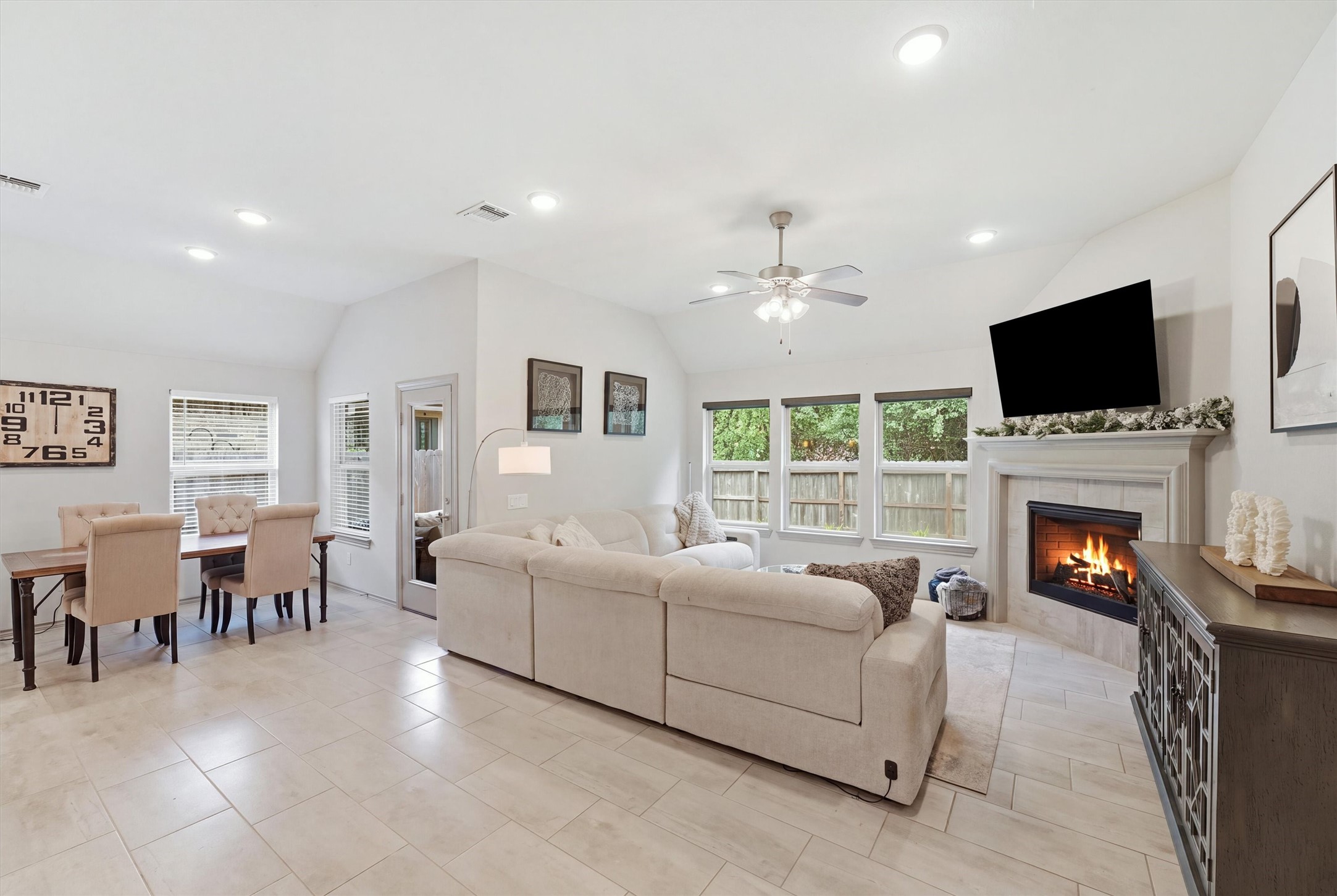 Open-concept living area featuring high ceilings, a comfortable seating arrangement, fireplace, and seamless connection to the dining area.
